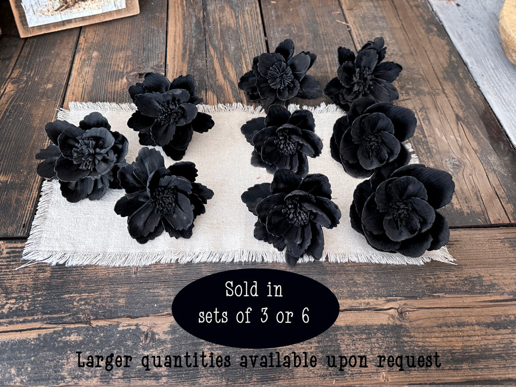 Black floral decorations on a white linen with text about quantity availability on a wooden surface.