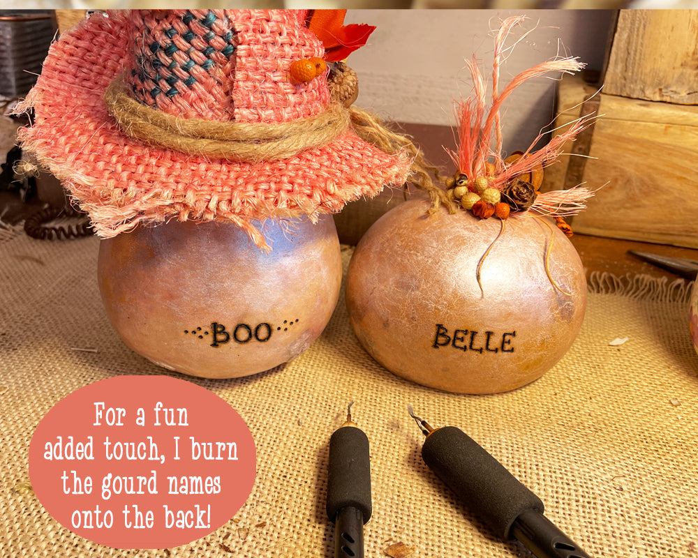 Showing the back of two pink ghost gourds with their names engraved in the shell. Their names are Boo and Belle