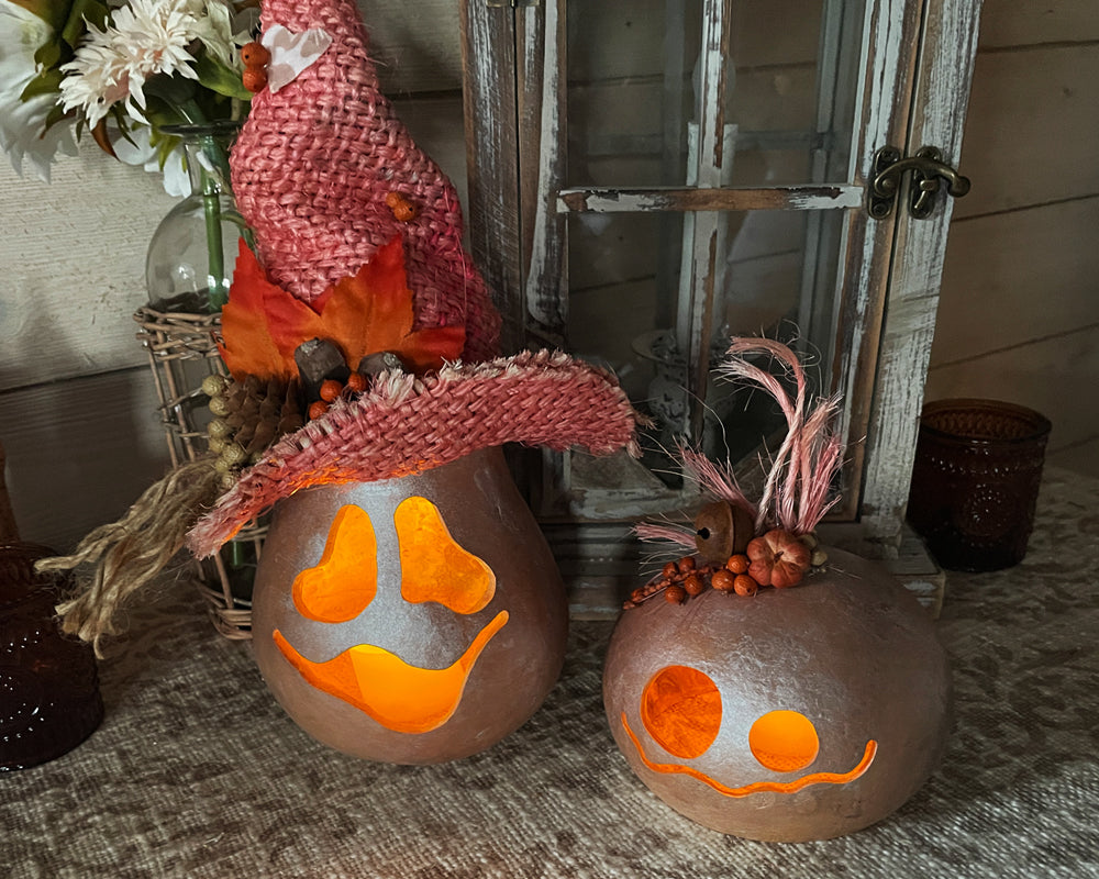 Two cute ghost decoration lit up for Halloween on an entry way table