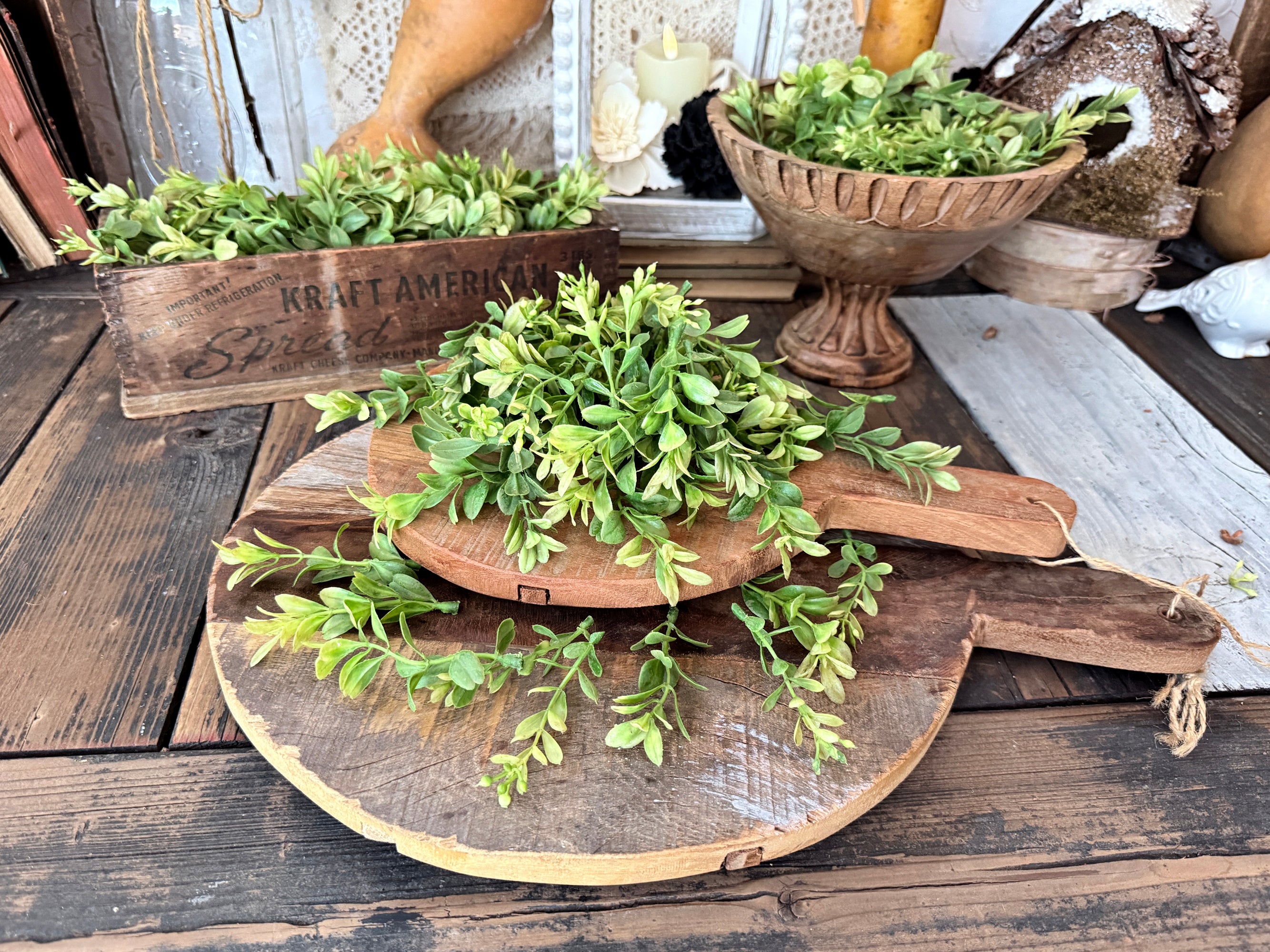 Decorative setup with green foliage on wooden bread board with a rustic background.