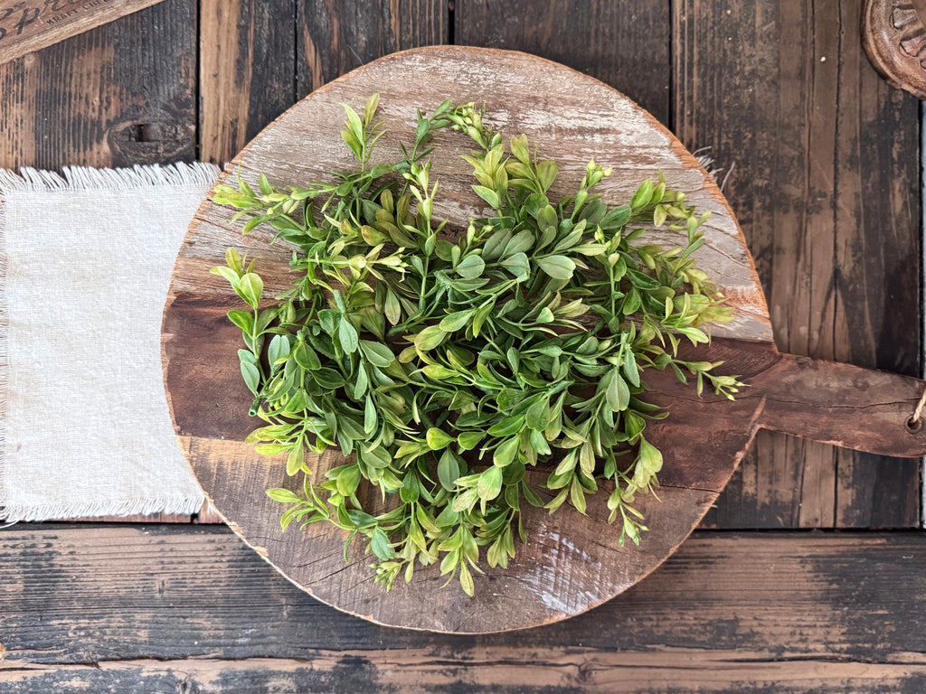 Vintage bread board with green leaves on a rustic wooden background