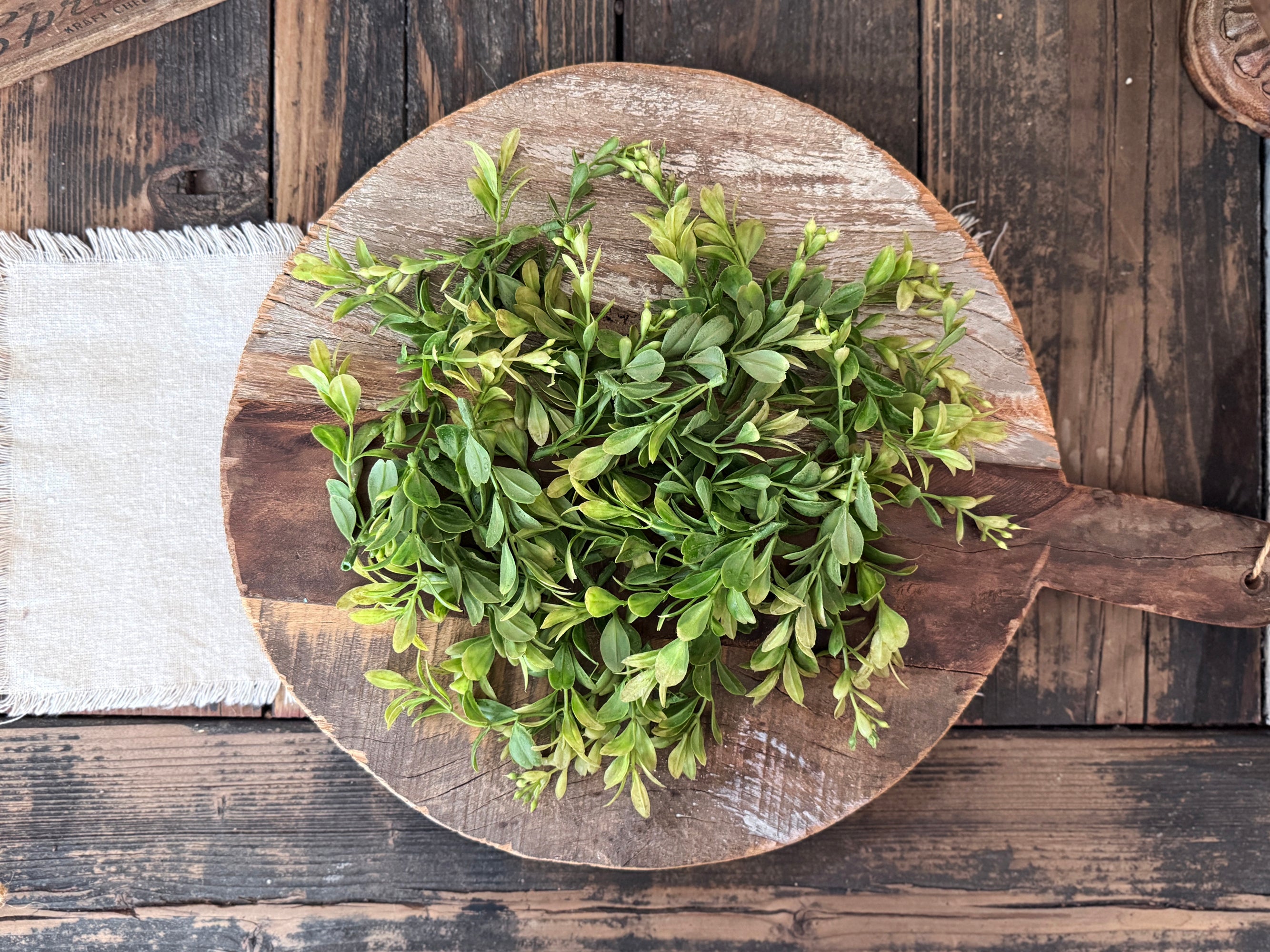 Vintage bread board with green leaves on a rustic wooden background