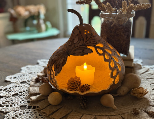 Carved gourd luminary sitting on a dinning room table with a candle inside. 