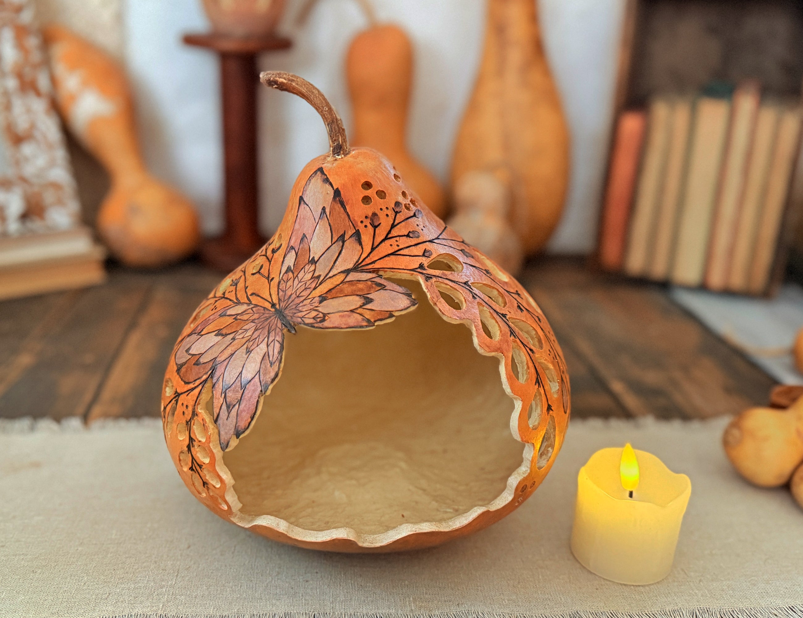 Carved Butterfly gourd luminary sitting on rustic table with vintage books in the background