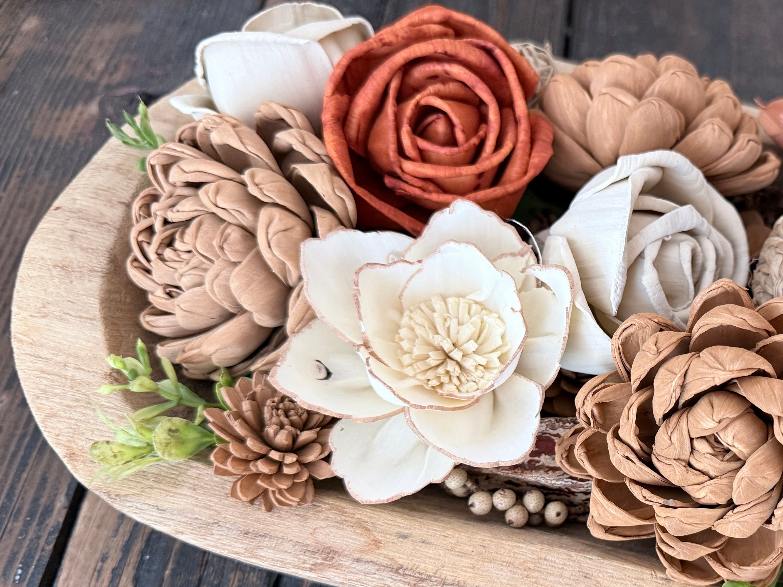 Decorative arrangement of flowers and pinecones in a wood dough bowl