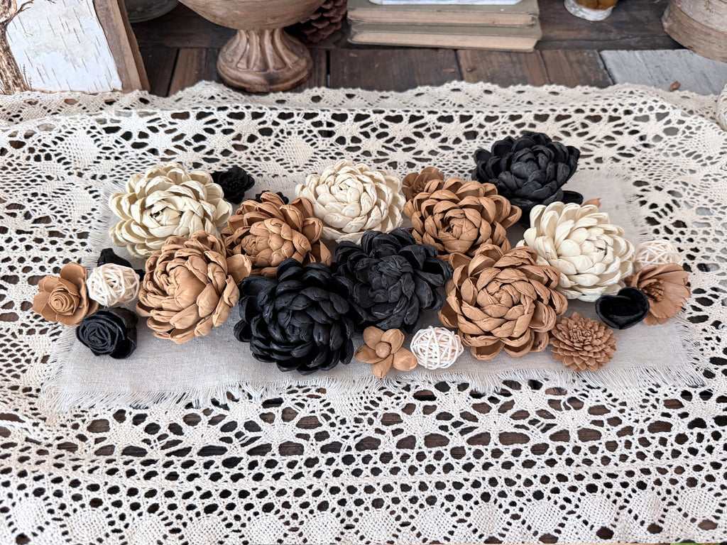 Decorative flowers in black, white, and brown on a lace tablecloth.