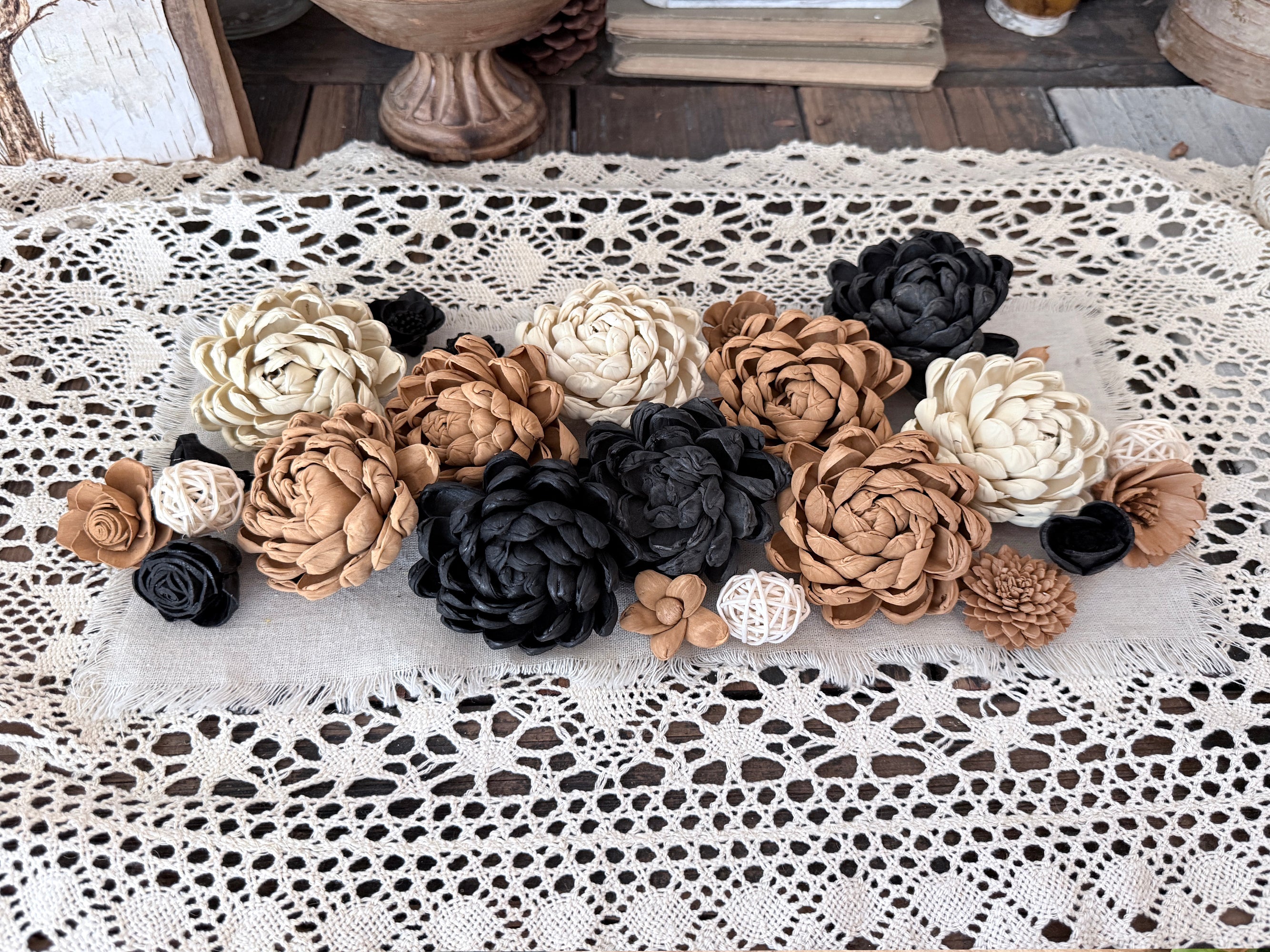 Decorative flowers in black, white, and brown on a lace tablecloth.