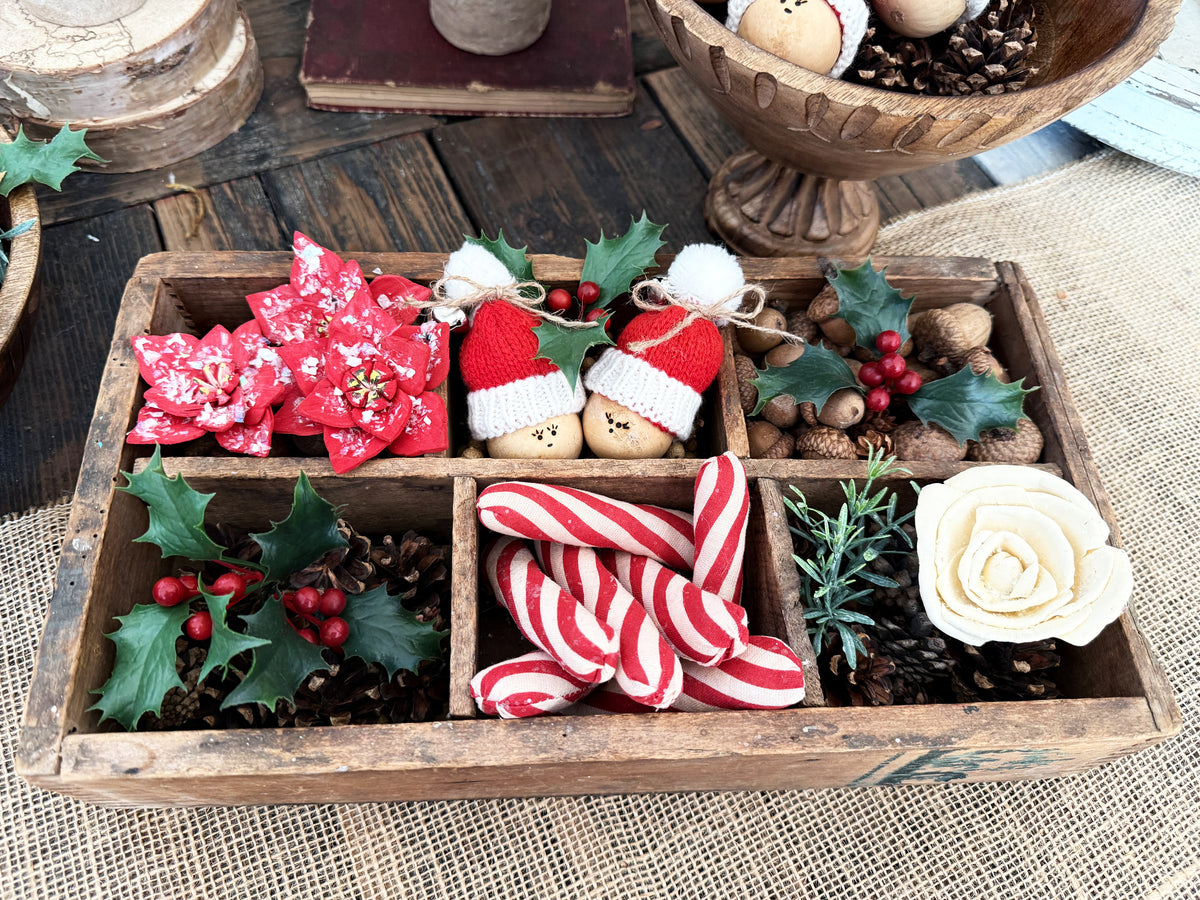 Vintage wood box with separators holds a Christmas display of Santa gourds, wood flowers and faux greenery. 