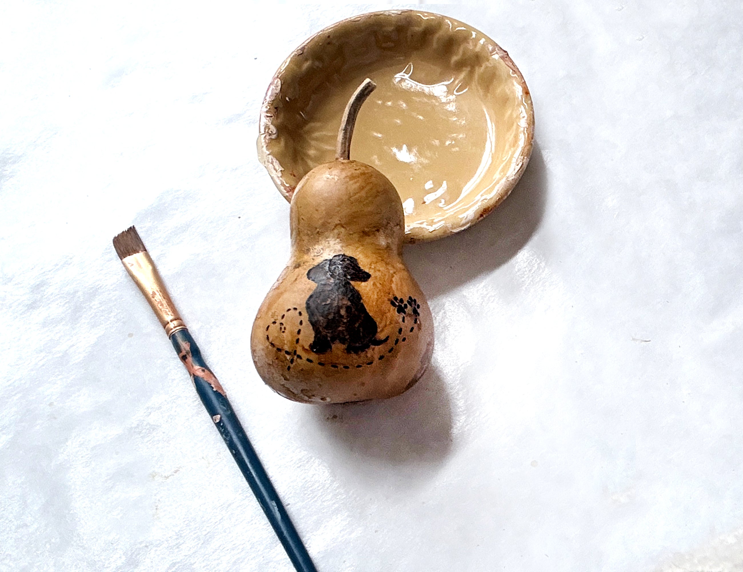 Ceramic bowl and Dachshund gourd with paintbrush on a white background