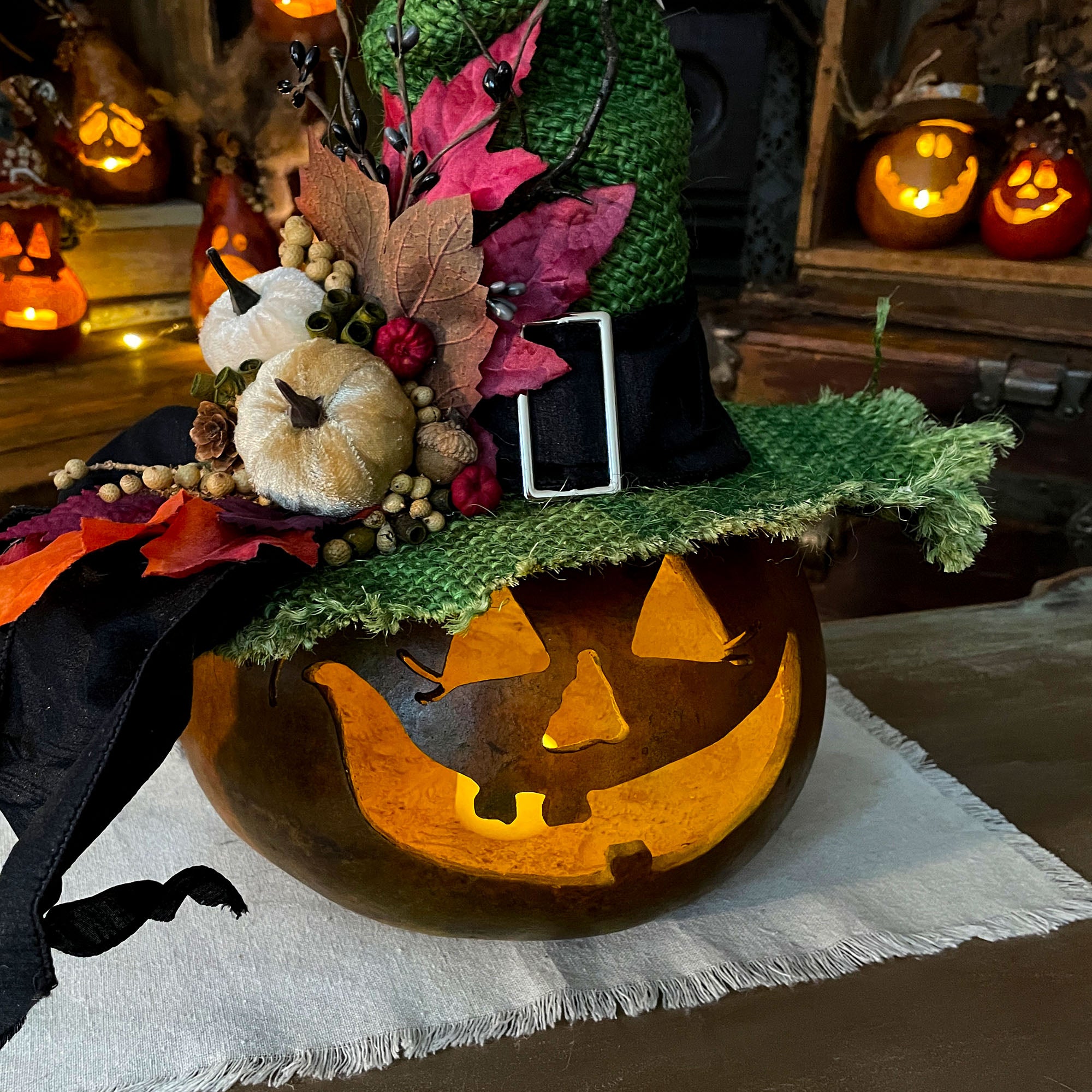 close-up image of the gourd witch decoration. Show the candle inside the pumpkin gourd, the green stain and decorative hat. 