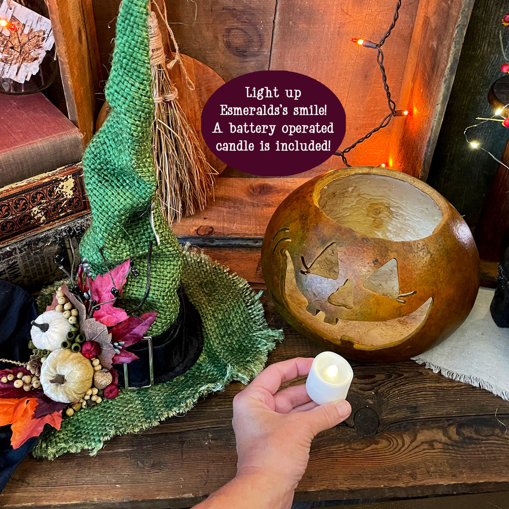 Shows the gourd character with the hat next to it. My hand is holding a battery operated candle that is included. 