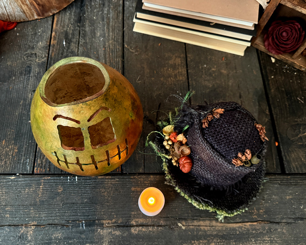 Top down view of monster gourd. Burlap top hat sits next to it with candle.