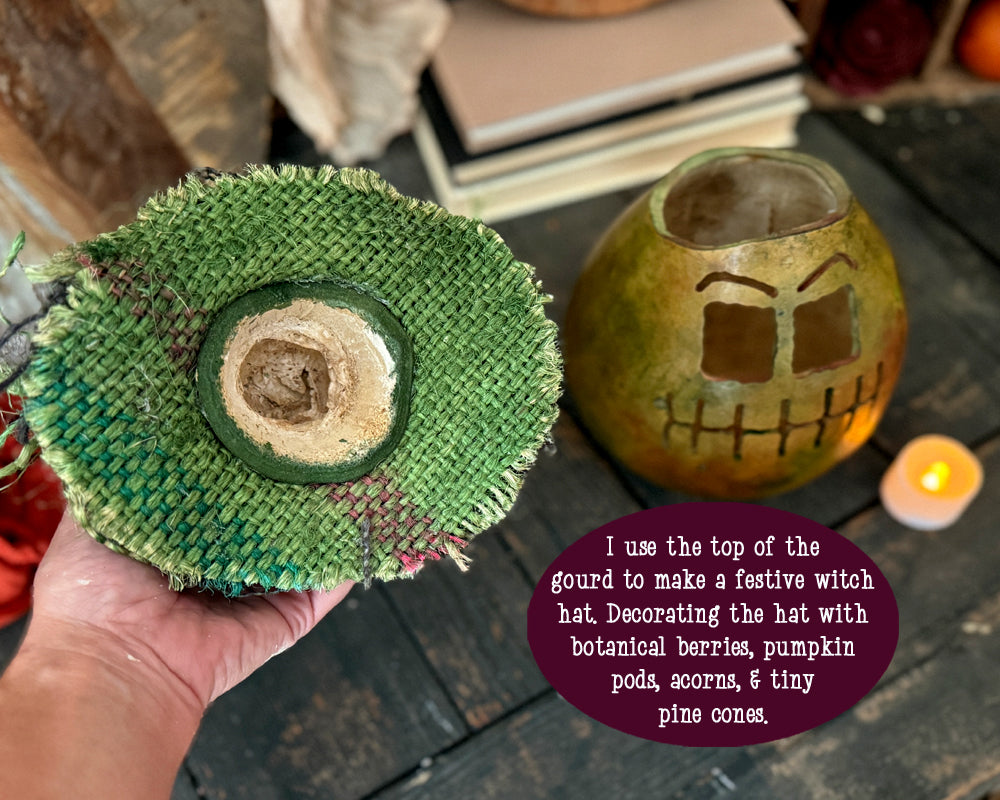 Underside of green burlap hat, held by a hand, with a decorative gourd and candle in the background.