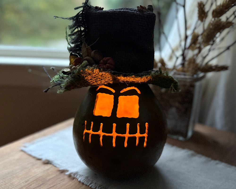 Carved ghostly gourd with candle lighting the face