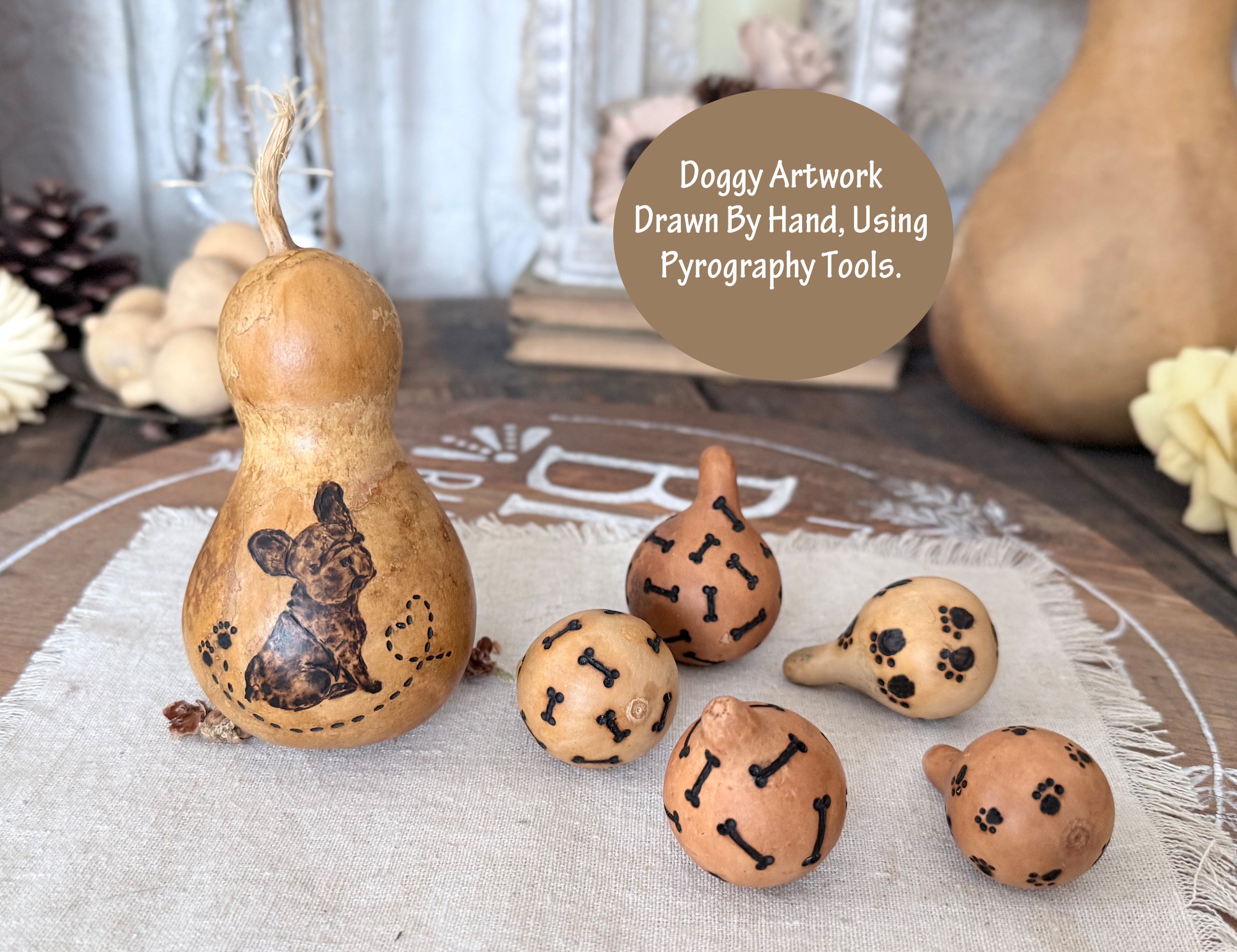 Decorative French Bulldog gourds with pyrography designs on a textured surface.