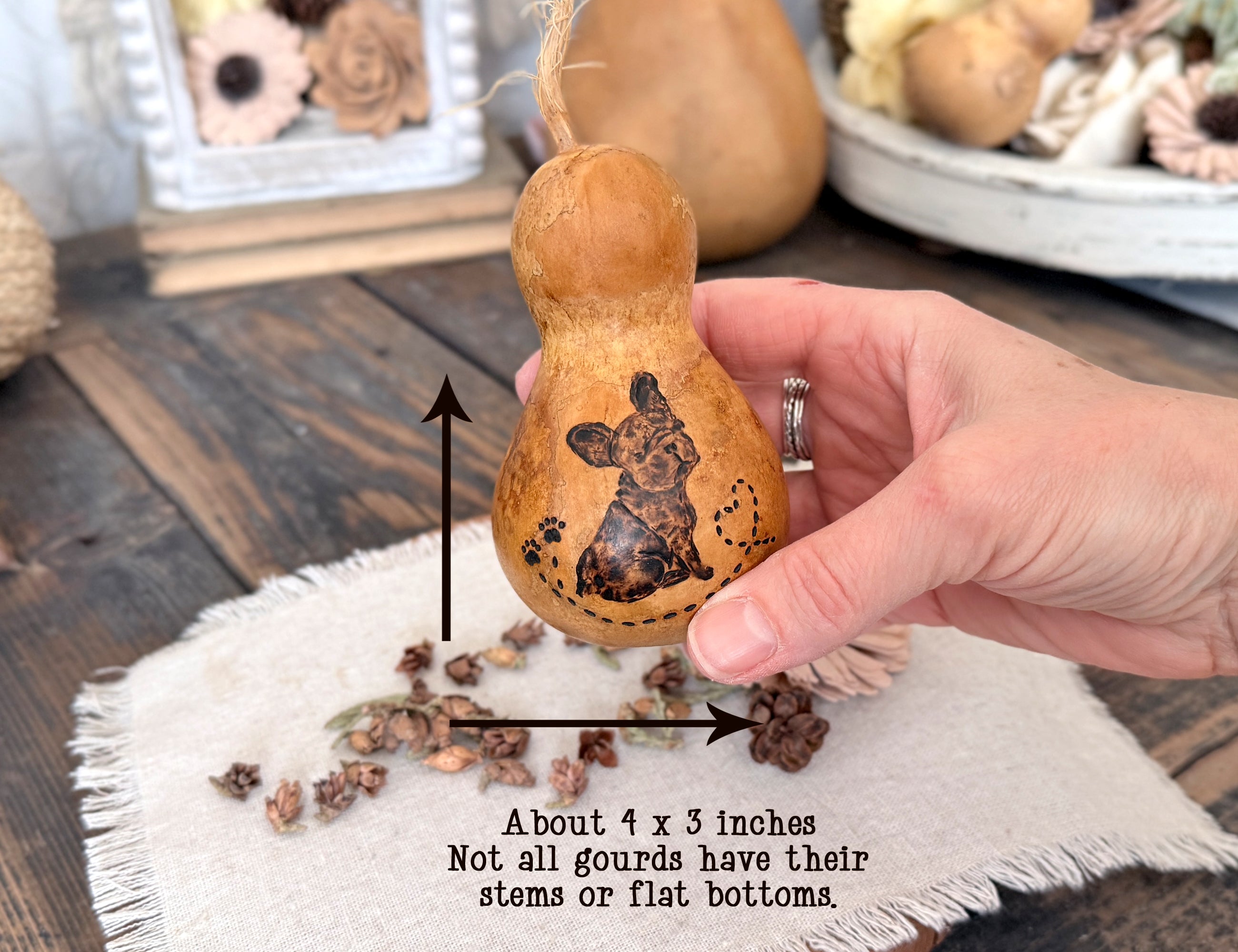 Hand holding a decorative gourd with a design, on a wooden surface with text overlay.