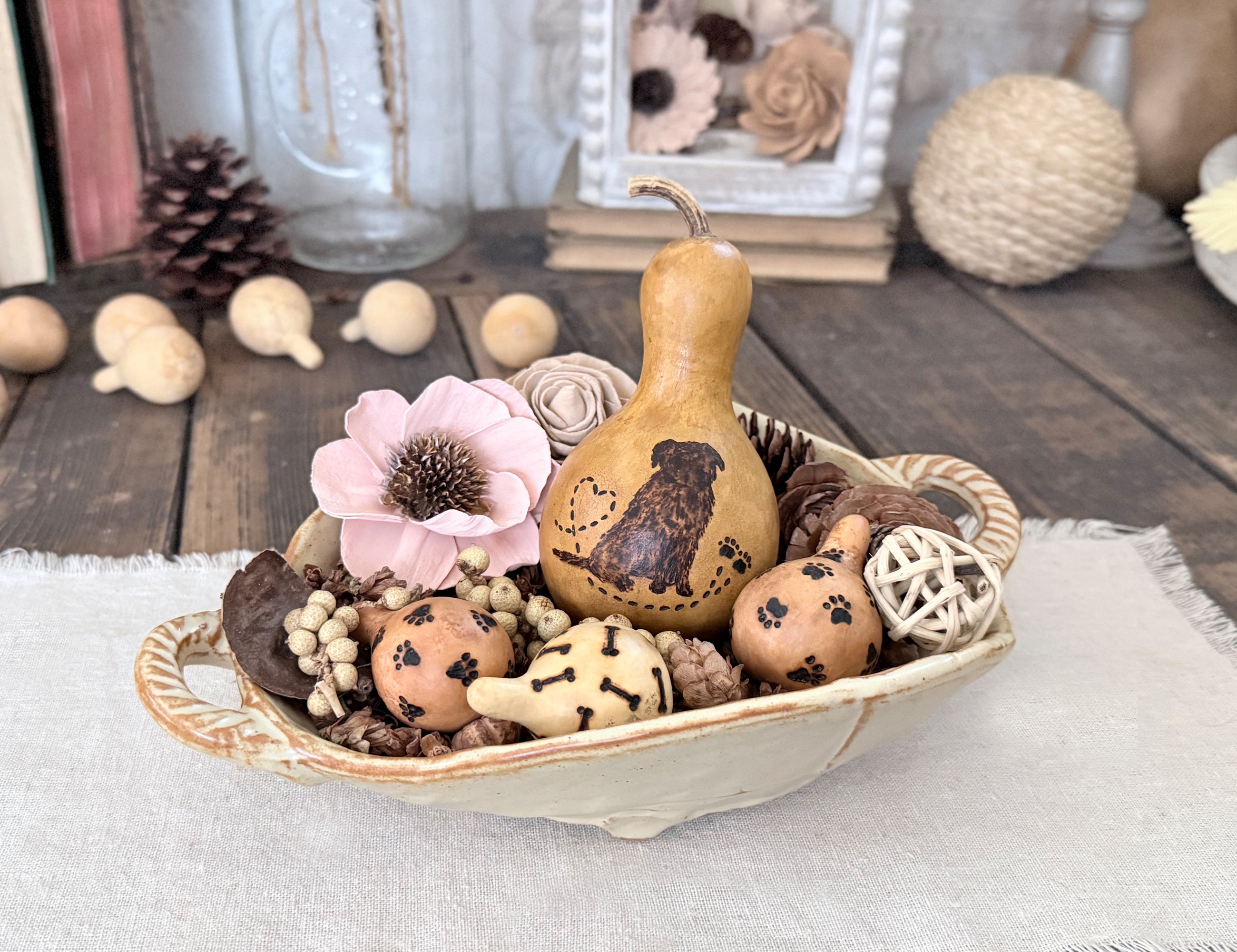 Decorative bowl with Golden Retriever gourd, wood flowers, and other ornaments on a wooden surface.
