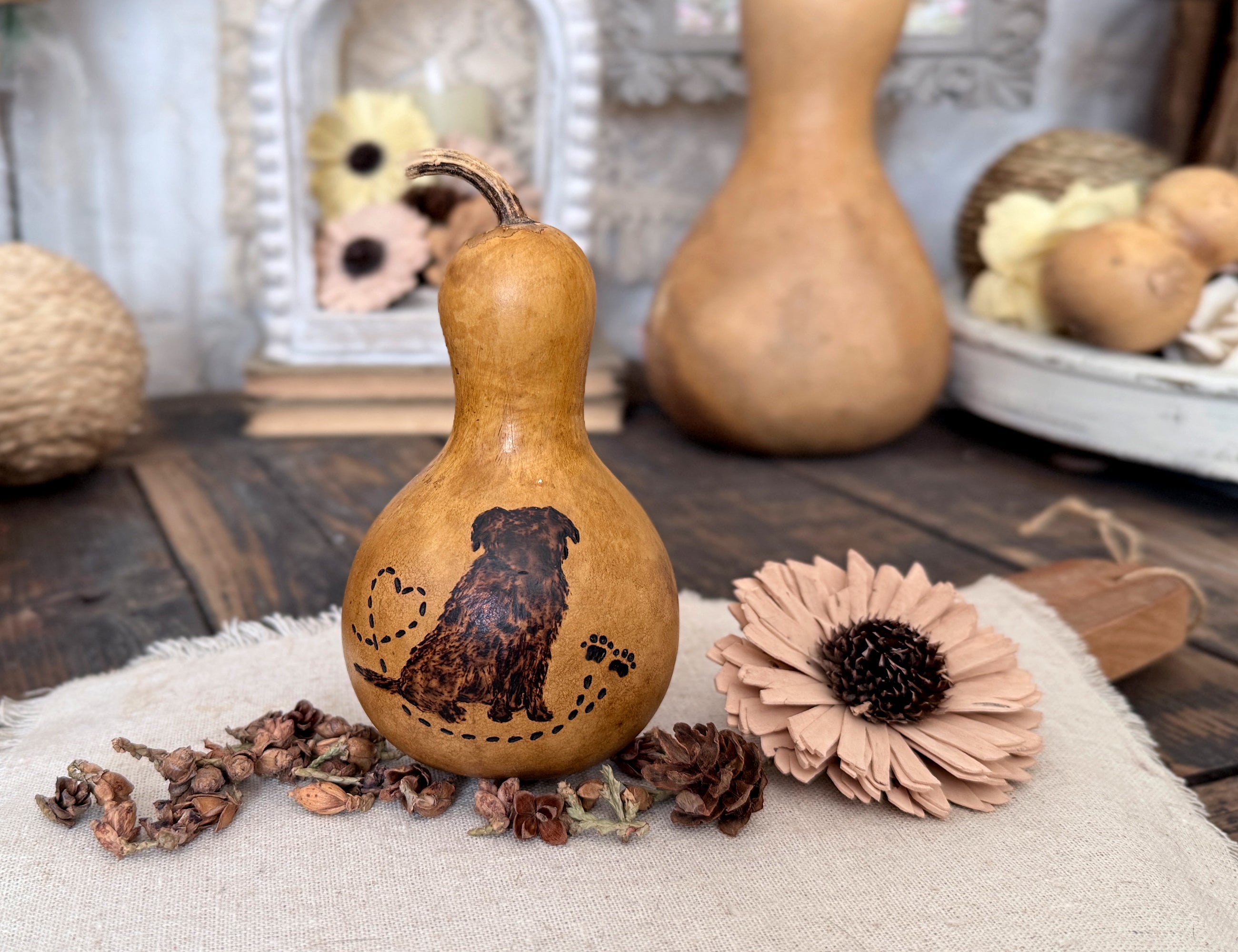 Decorative Golden Retriever gourd with a carved design on a wooden surface with flowers and pinecones.