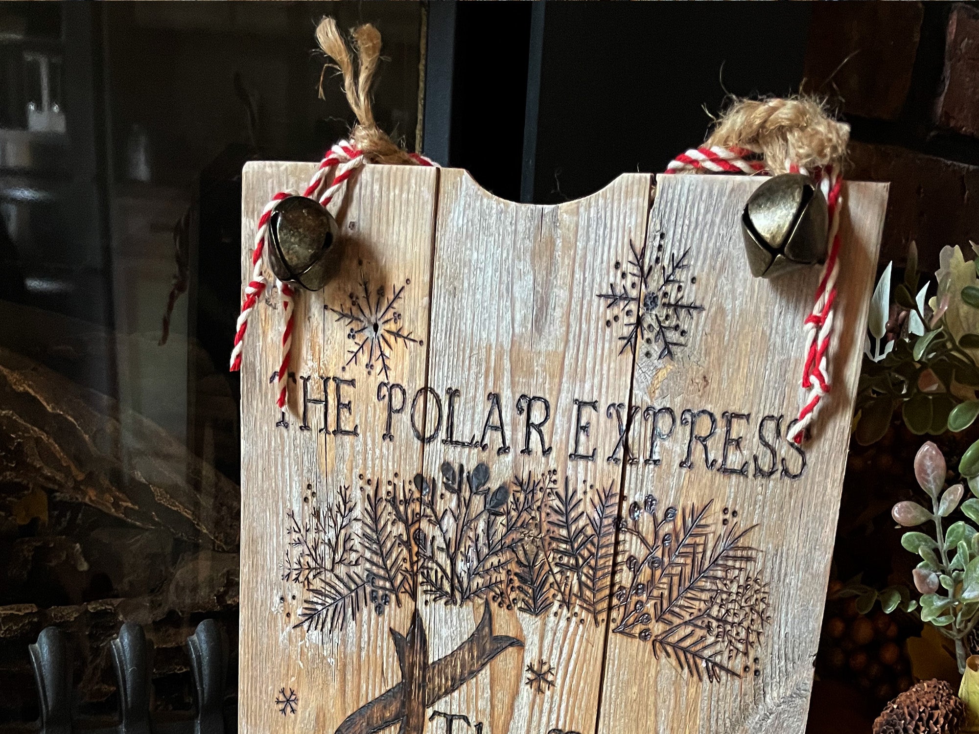 Wooden sign with 'The Polar Express' text and festive design, hanging against a dark background.