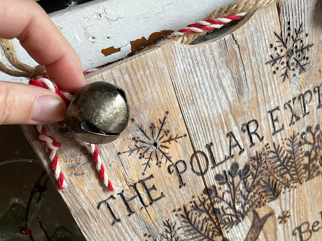 Wooden ornament with 'The Polar Express' text and snowflakes, held by a hand.