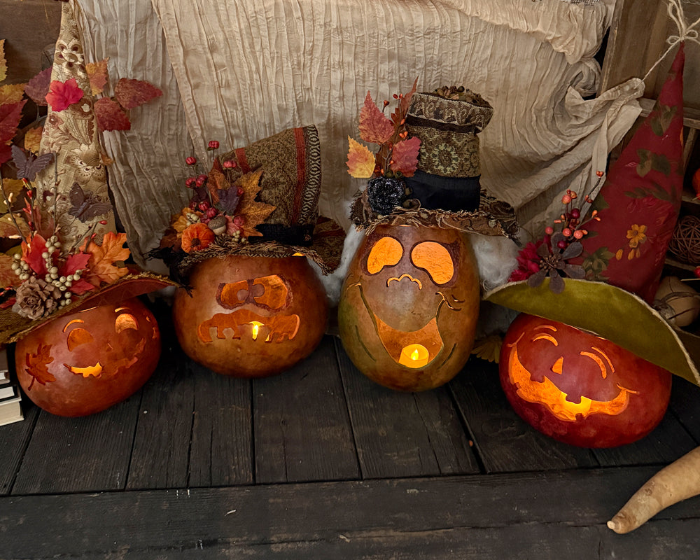 Decorative pumpkins with carved faces on a wooden surface, surrounded by autumn leaves and festive decorations.