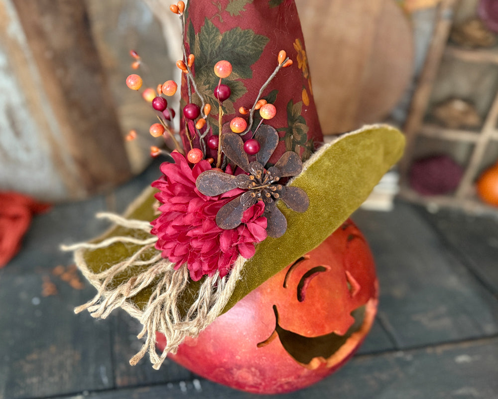 Decorative autumn-themed pumpkin gourd with flowers and leaves on a wooden surface