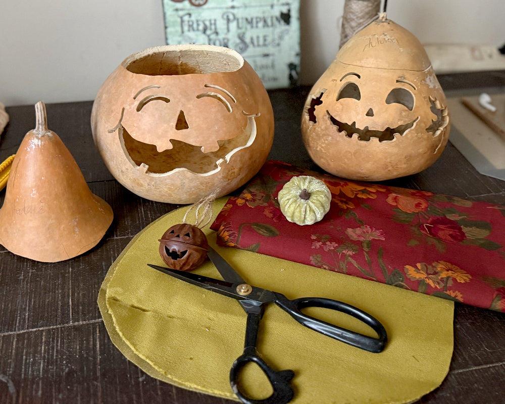 Carved pumpkins with smiling faces on a table with scissors and fabric