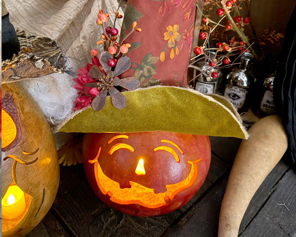 Carved pumpkin with a smiling face, lit from within, surrounded by decorative elements on a wooden surface.