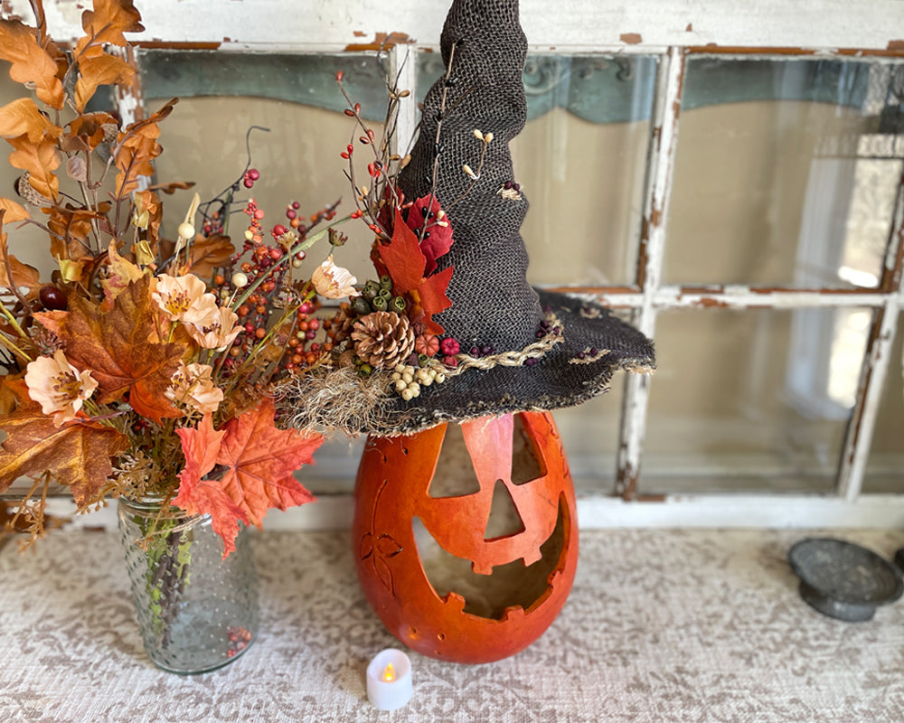 Halloween-themed decoration with a jack-o'-lantern, witch hat, and autumn leaves.