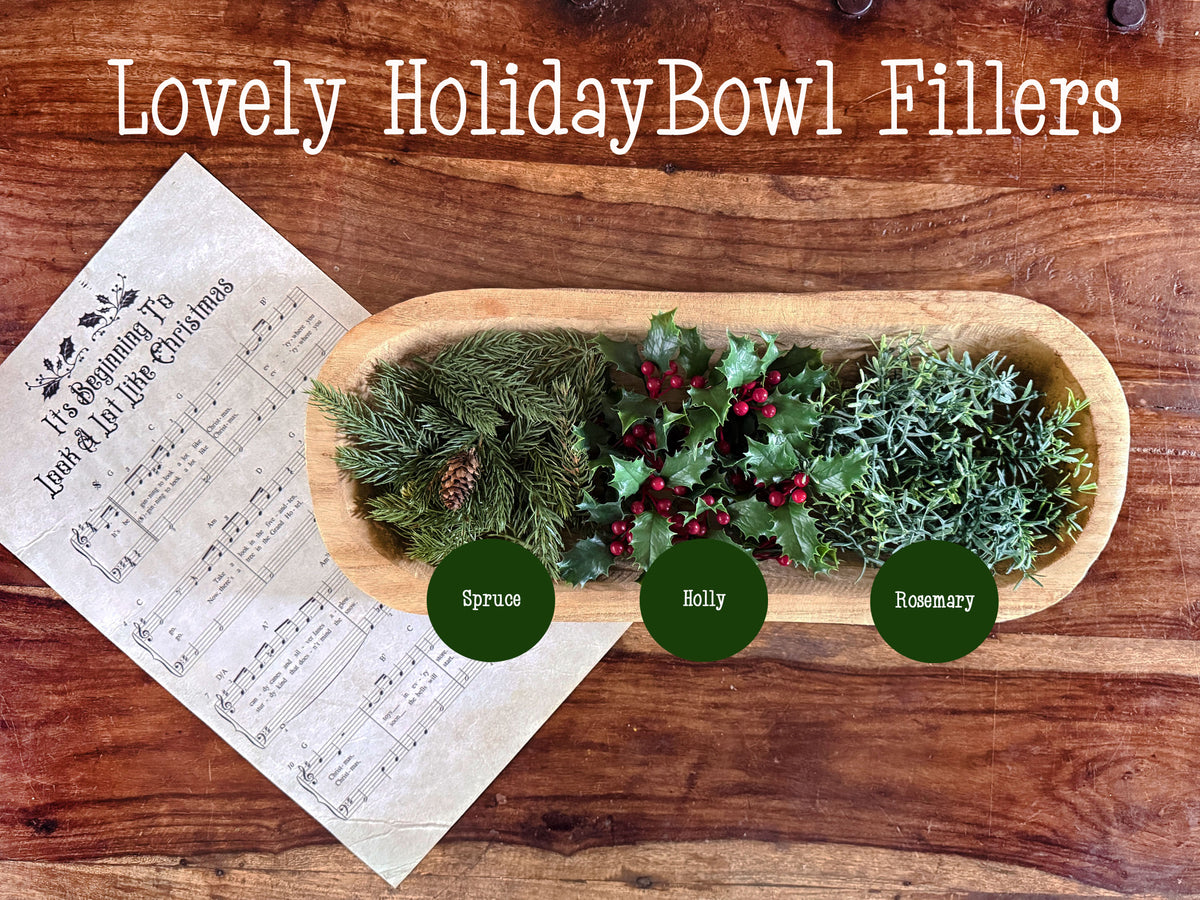 A dough bowl arranegrment showing and assortment of winter greenery in spruce, holly, and rosemary