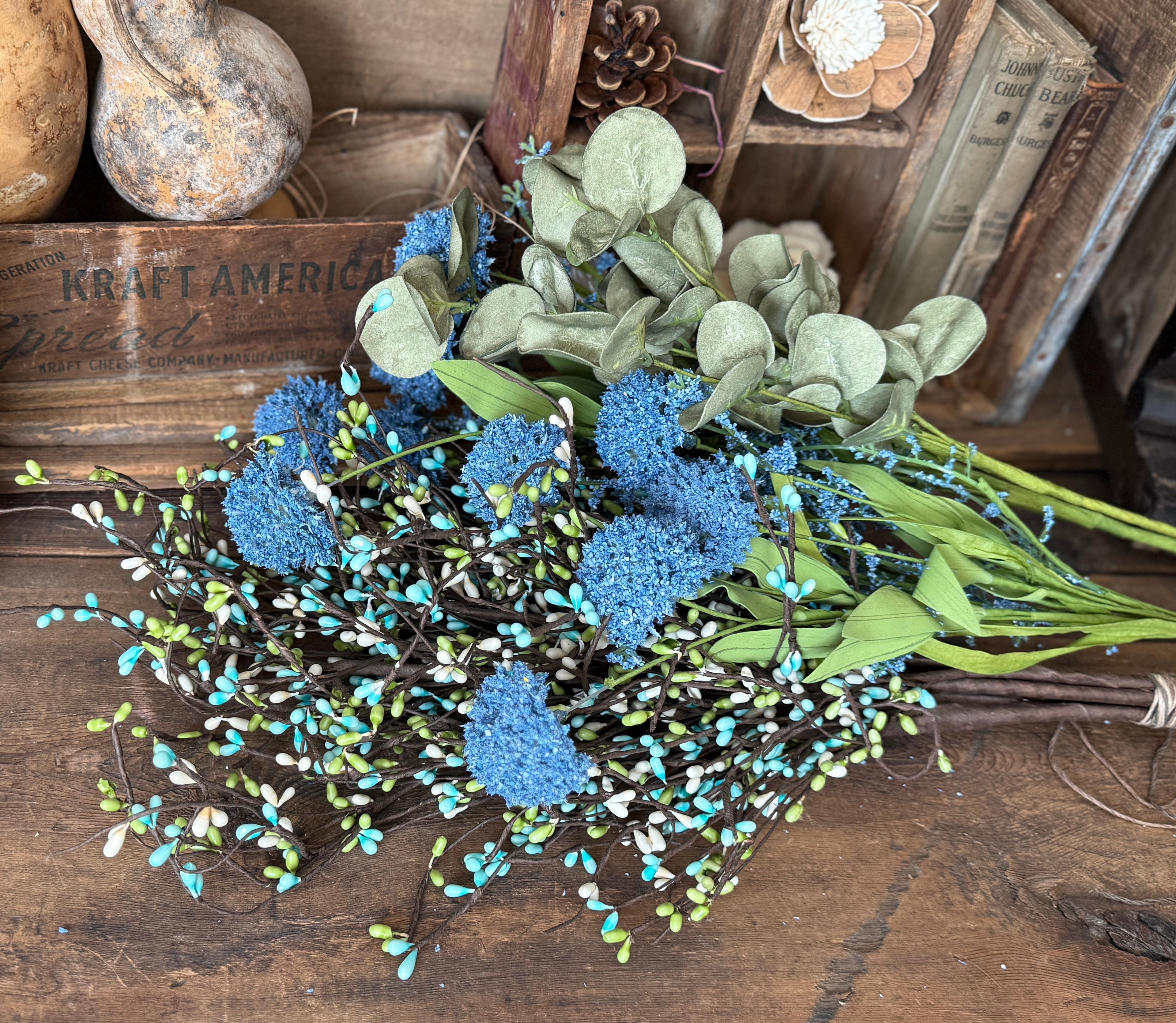 Bouquet of blue flowers and green leaves on a wooden surface with rustic background