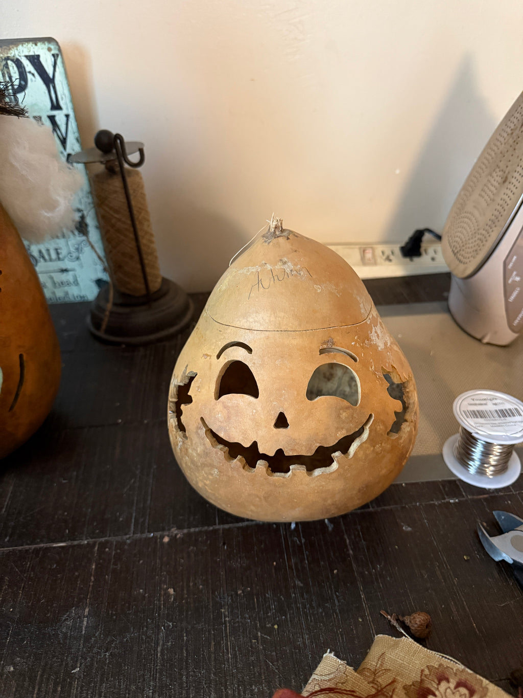 Decorative pumpkin lantern with carved face on a stand against a neutral background