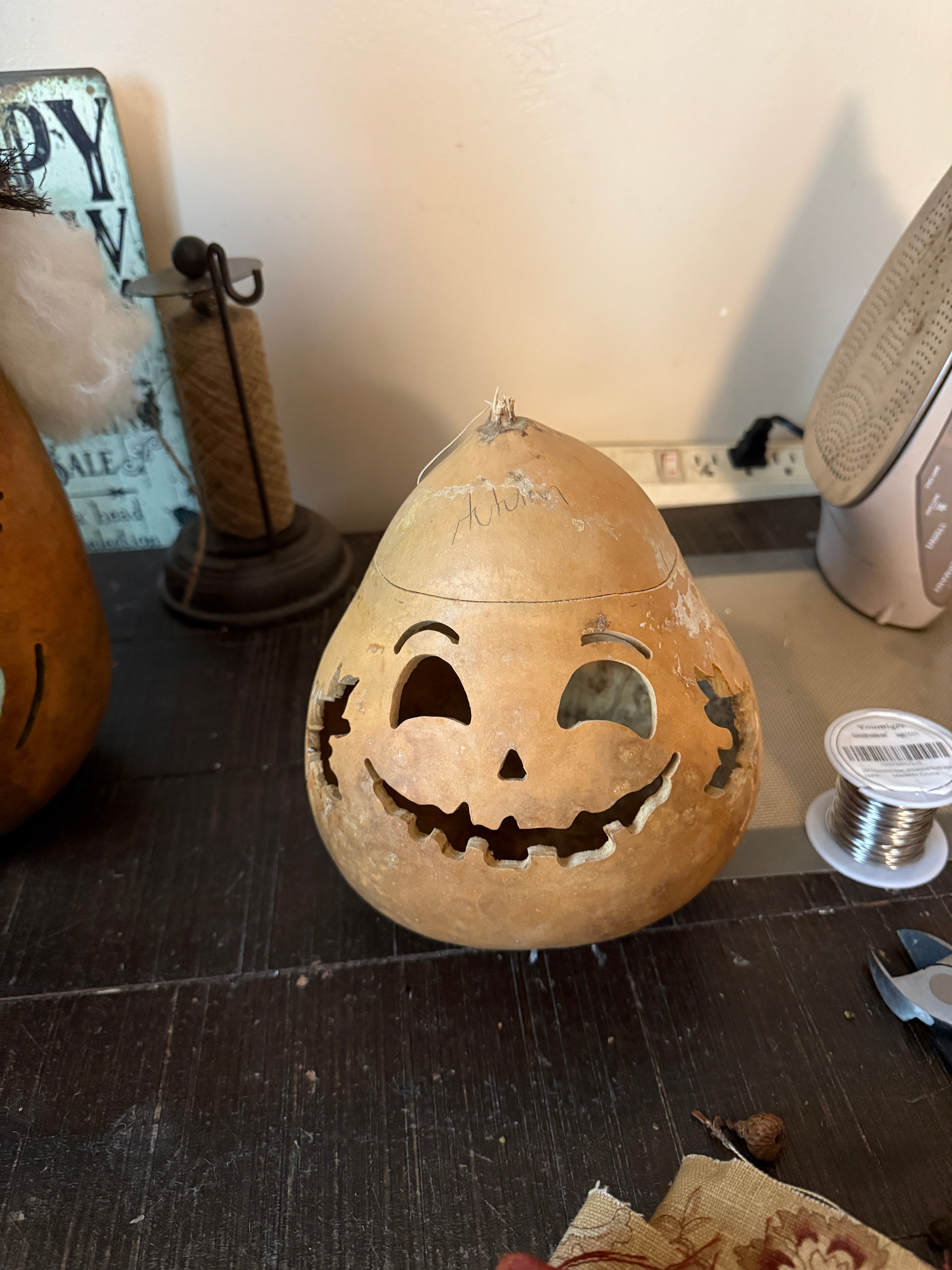 Decorative pumpkin lantern with carved face on a stand against a neutral background