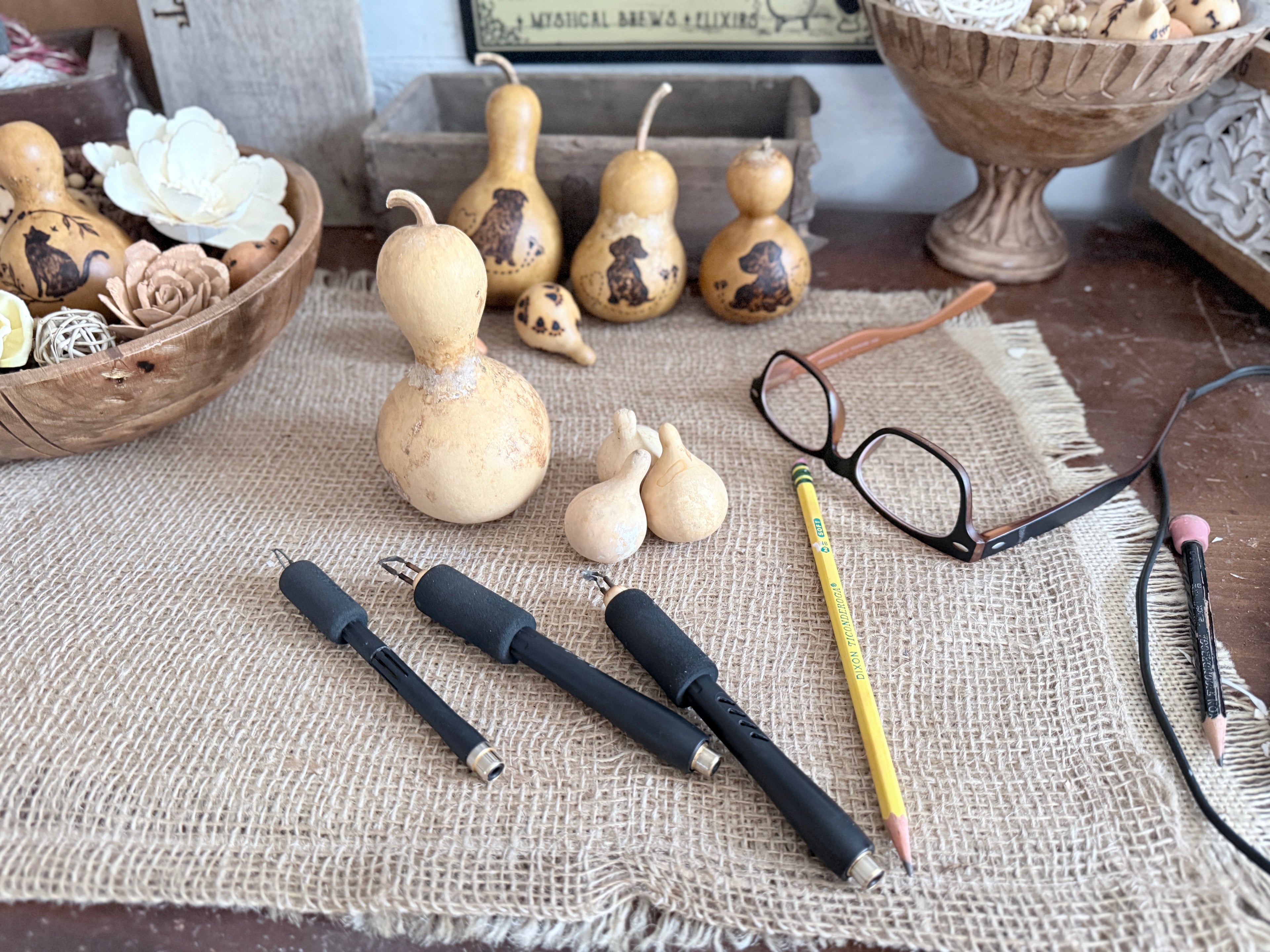 Decorative gourds, pens, and a pencil on a textured surface with a blurred background.