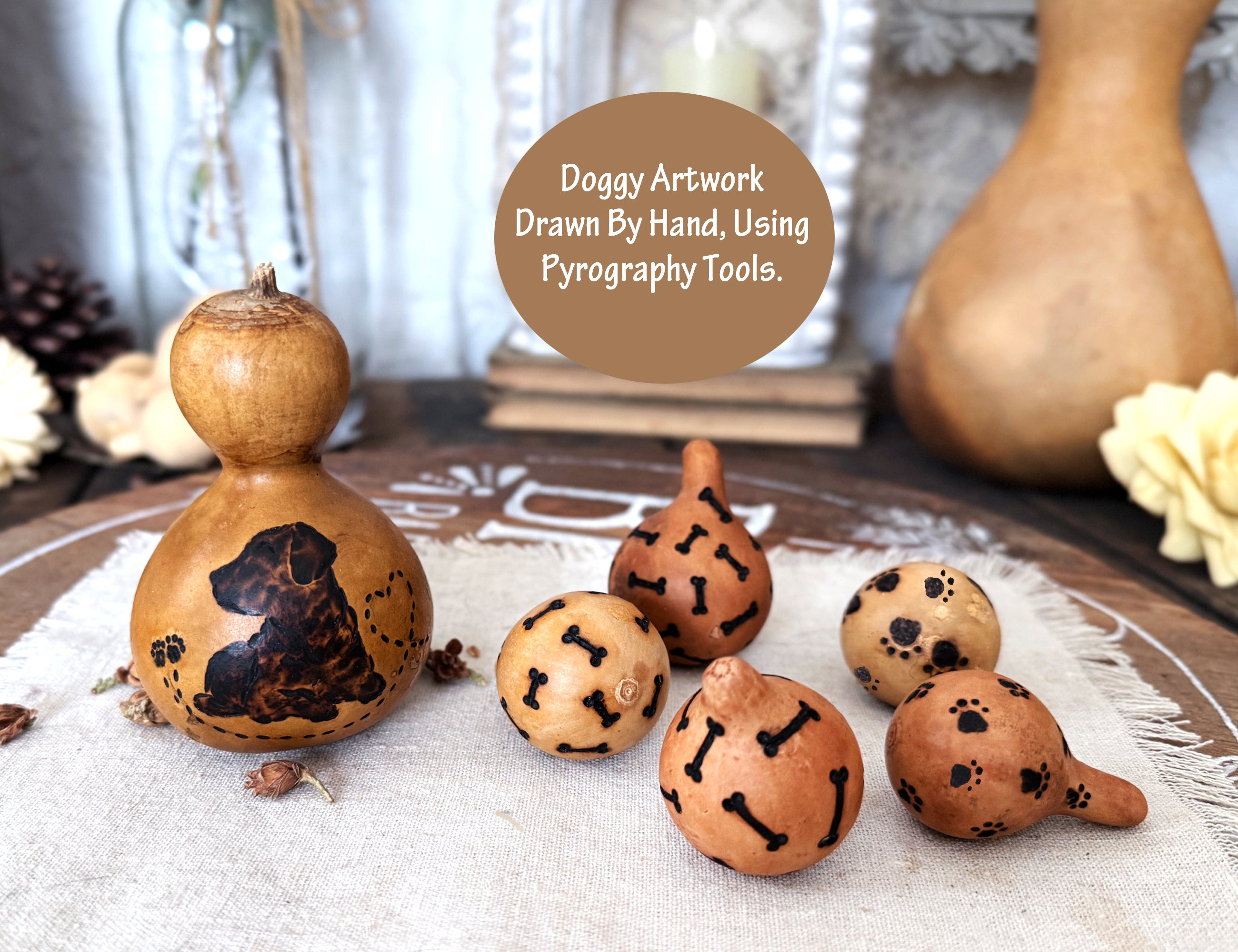 Decorative gourds with doggy artwork using pyrography tools on a textured surface.