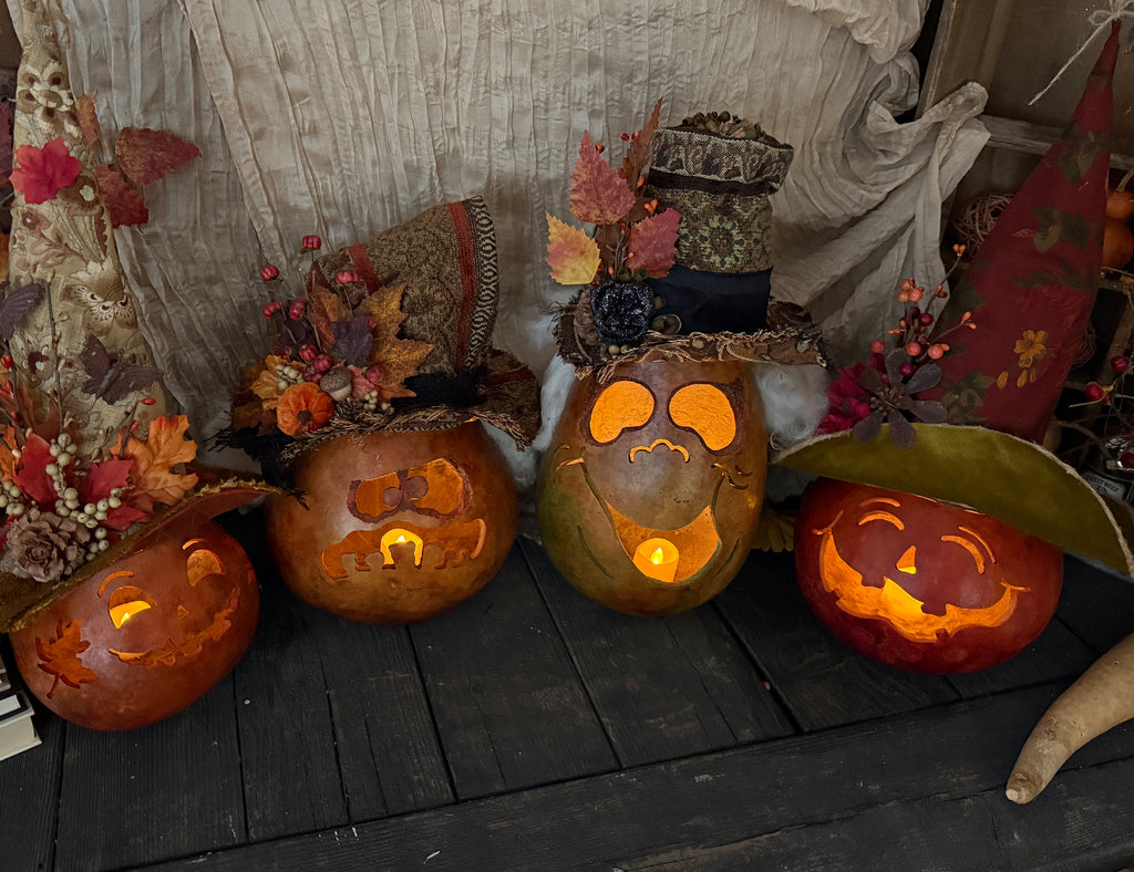 Carved pumpkins with glowing lights on a wooden surface, surrounded by autumn decorations.
