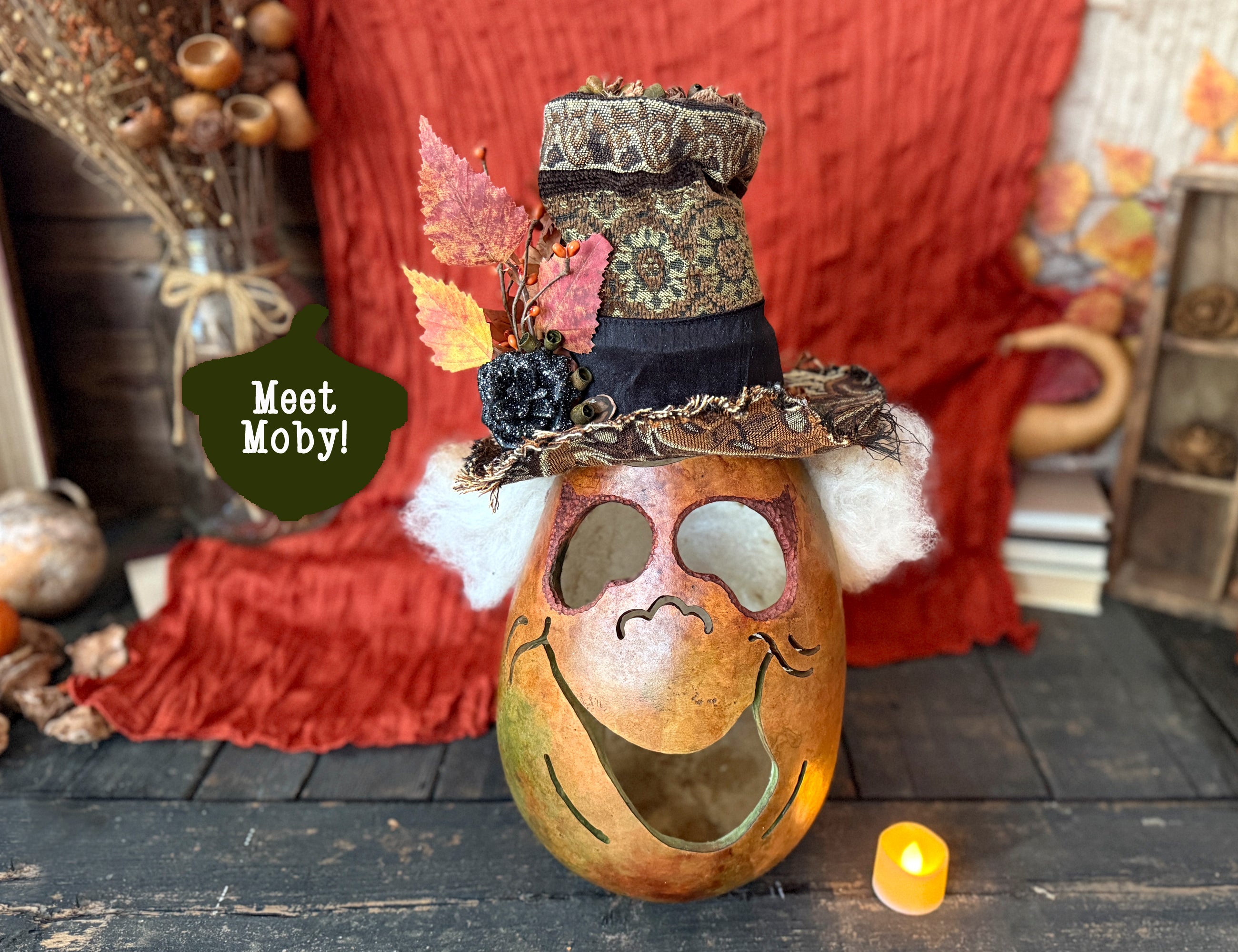 Decorative silly gourd with face and top hat on a rustic surface with autumn leaves and candle.