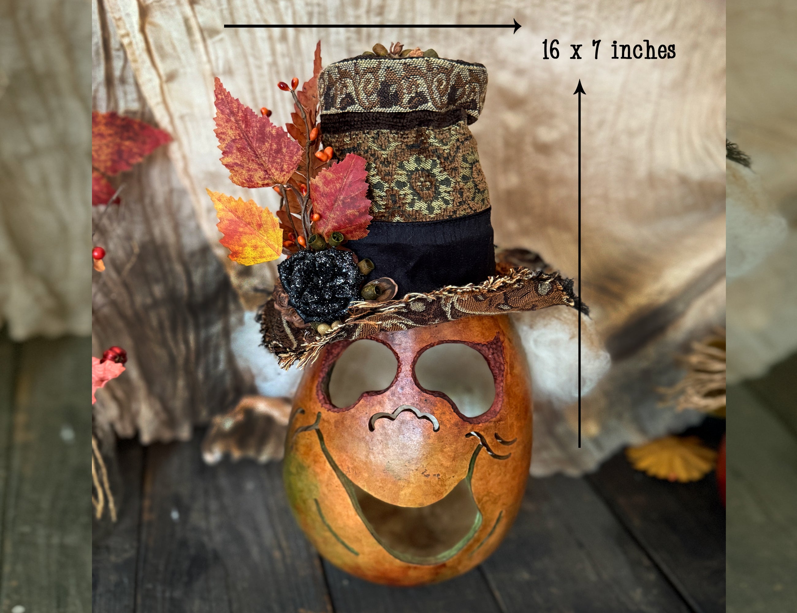 Decorative pumpkin with a hat and autumn leaves on a wooden surface, with dimensions indicated.