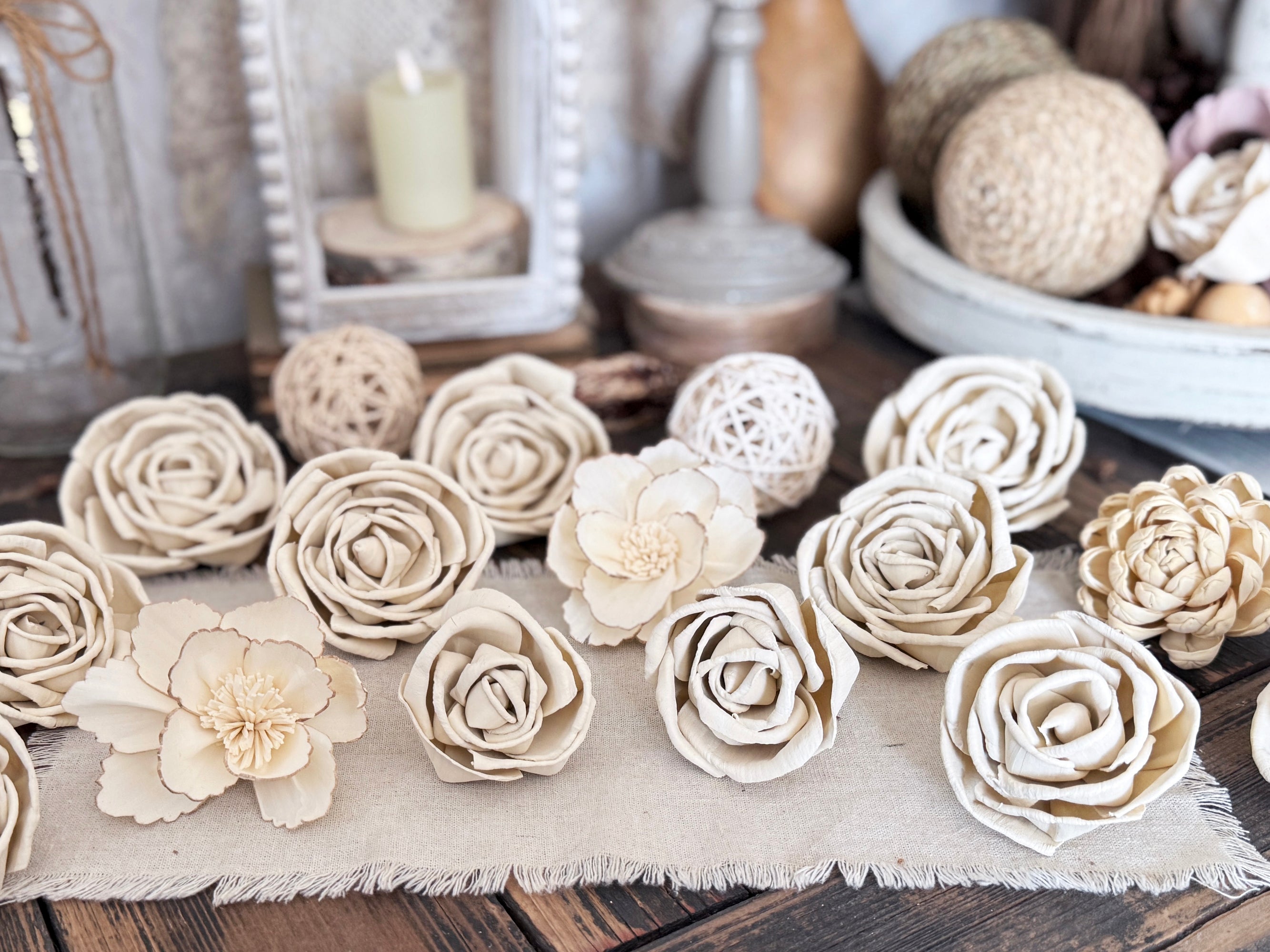 Antique white flower blossoms laid out on a wooden surface with decorative items in the background.