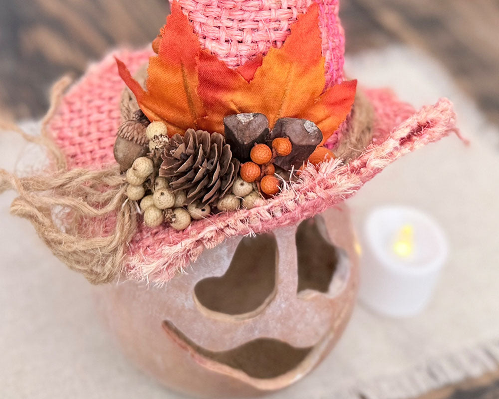 A top down view of Boo's pink witch hat showing orange leaves and dried pods.