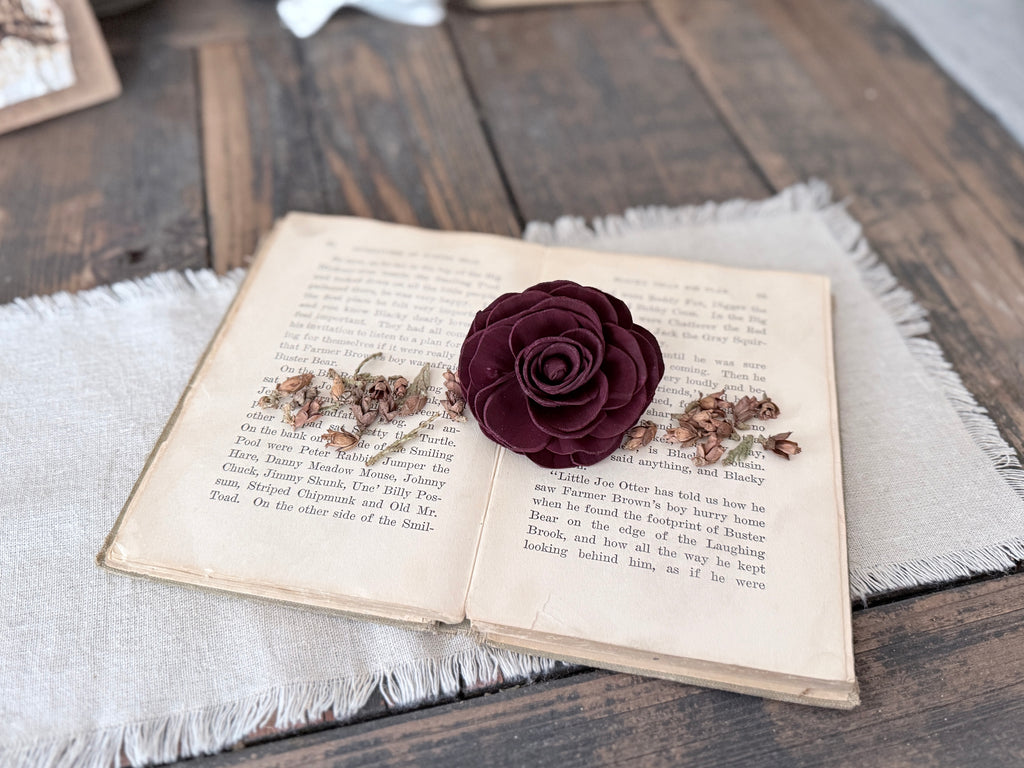 A wood flower blossom laid out on open book pages. 