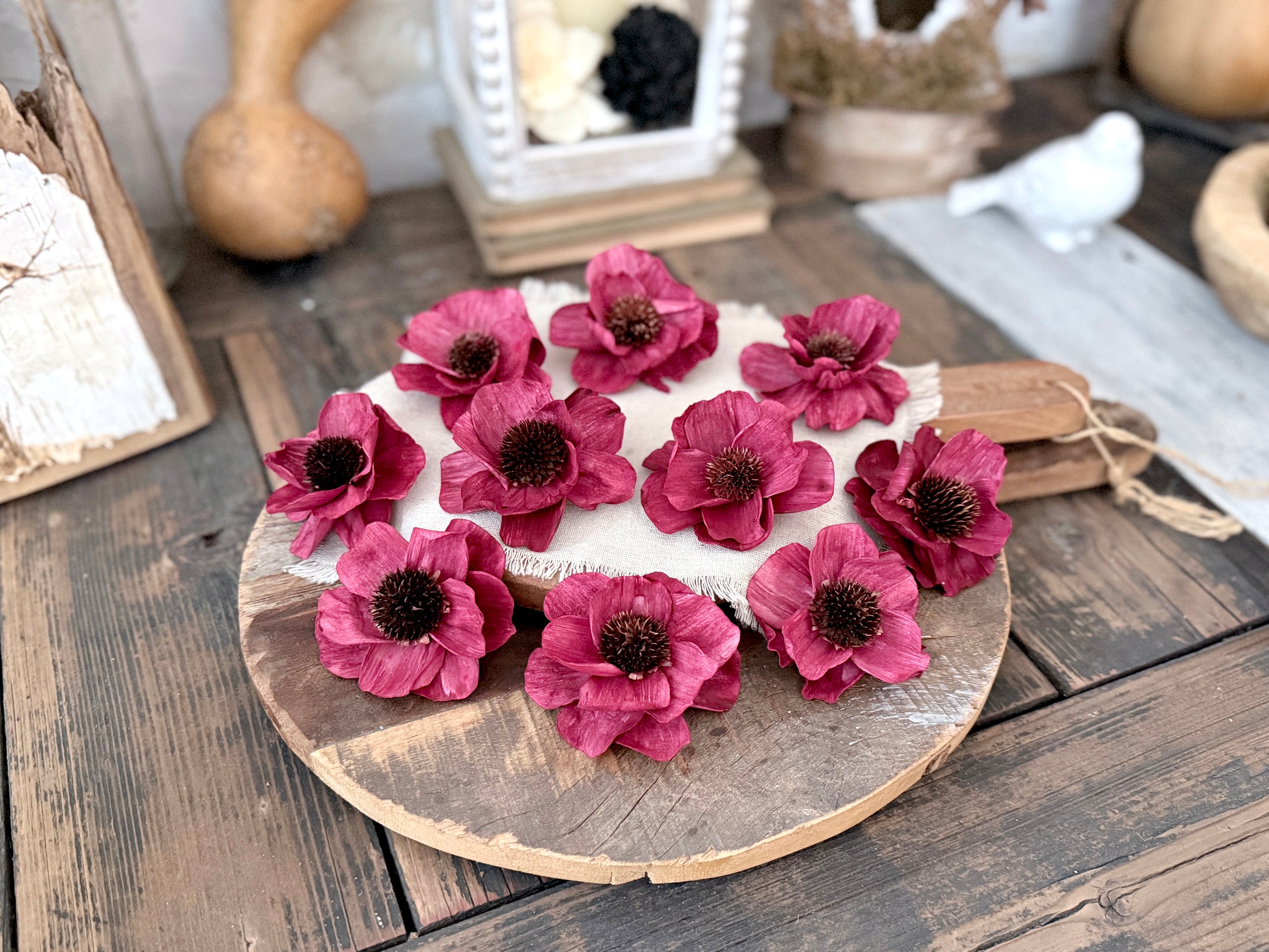 Red flowers on a round wooden bread board with a rustic background