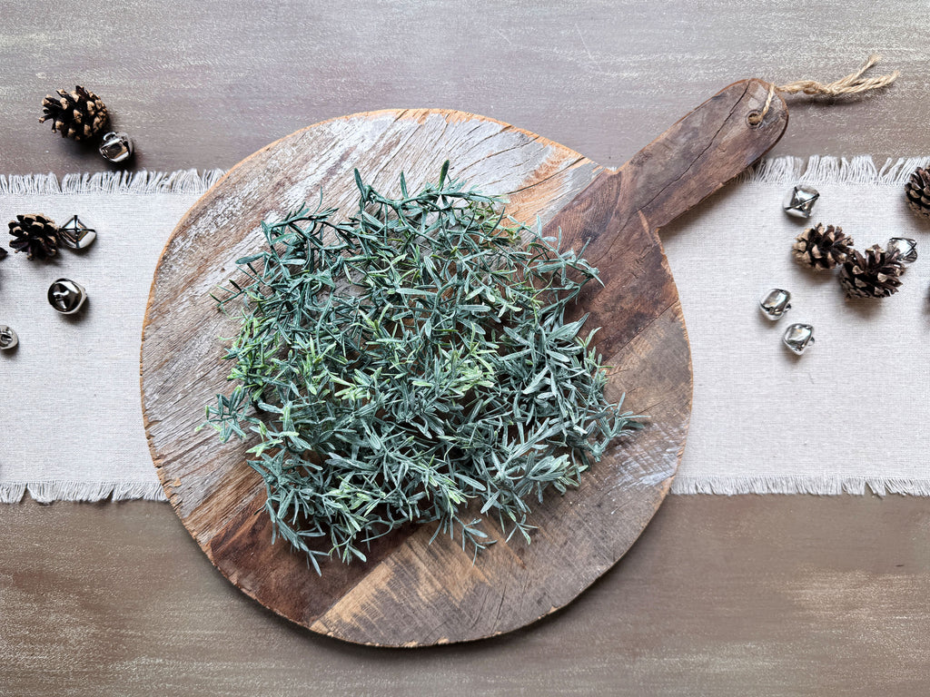 A vintage style bread board with sprig of white dusted rosemary