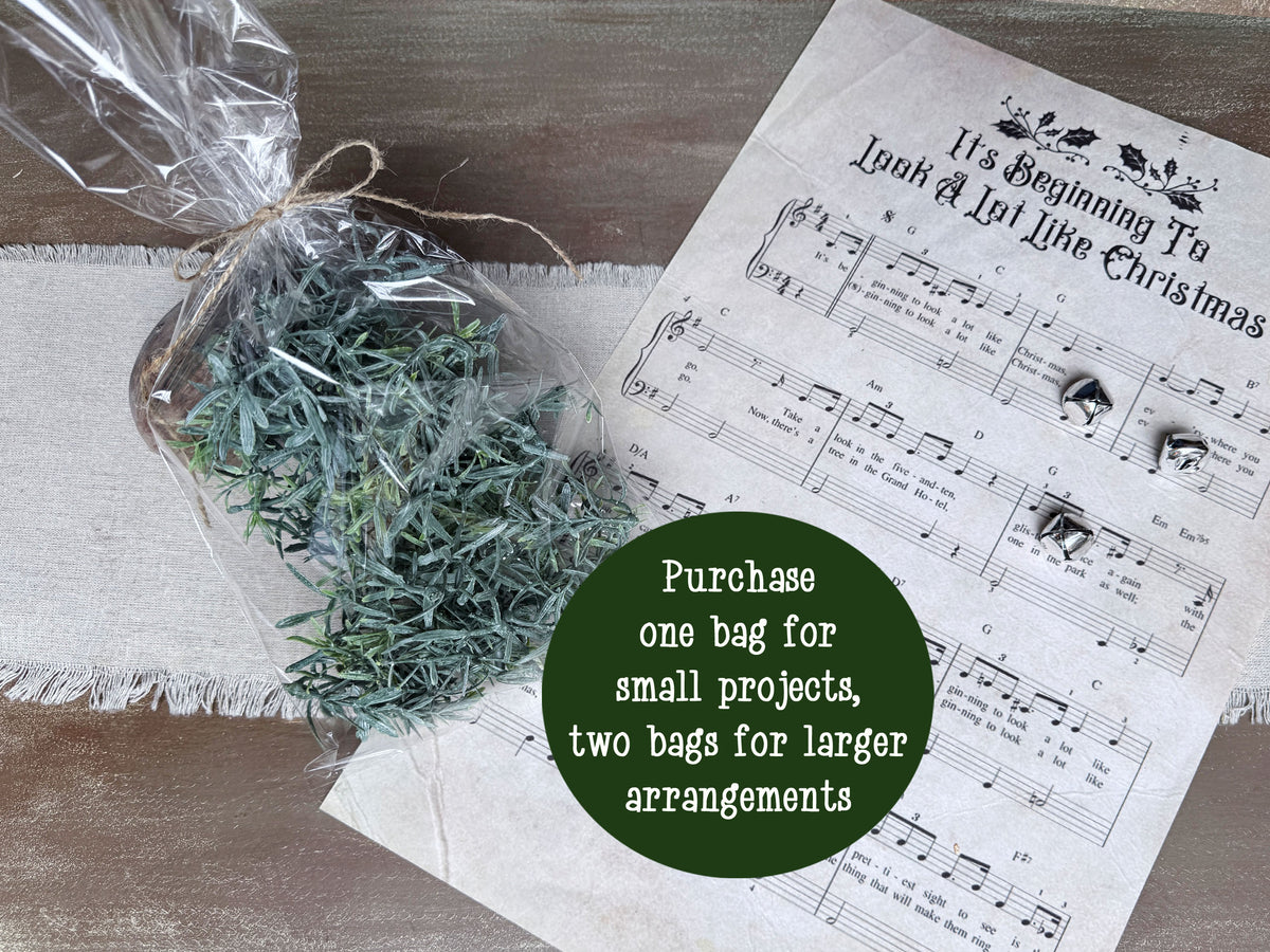A clear bag of rosemary bowl filler laid next to a Christmas Music sheet. 