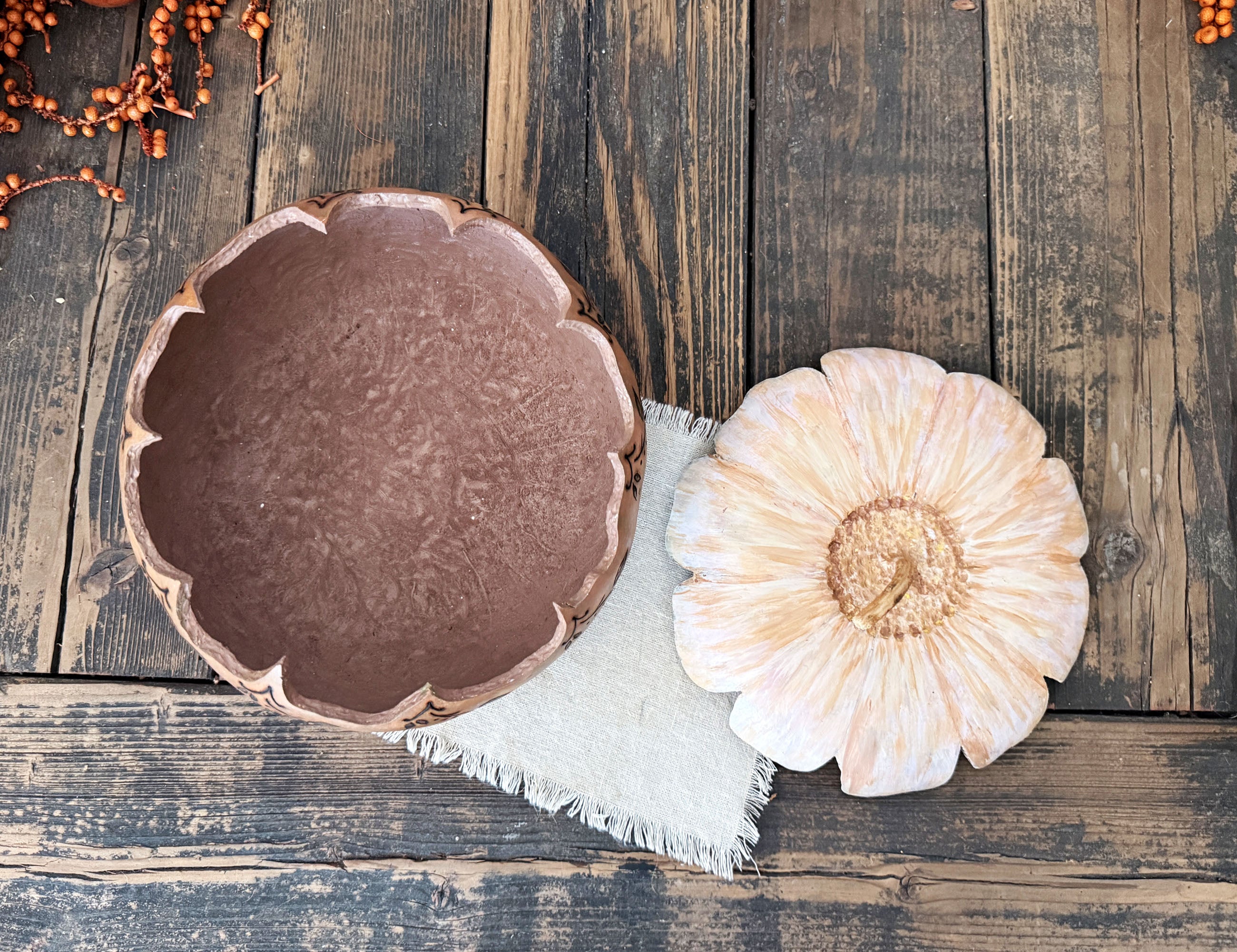 A decorative gourd bowl with a flower shaped lid. the bowl is brown and the lid is painted like a white daisy.