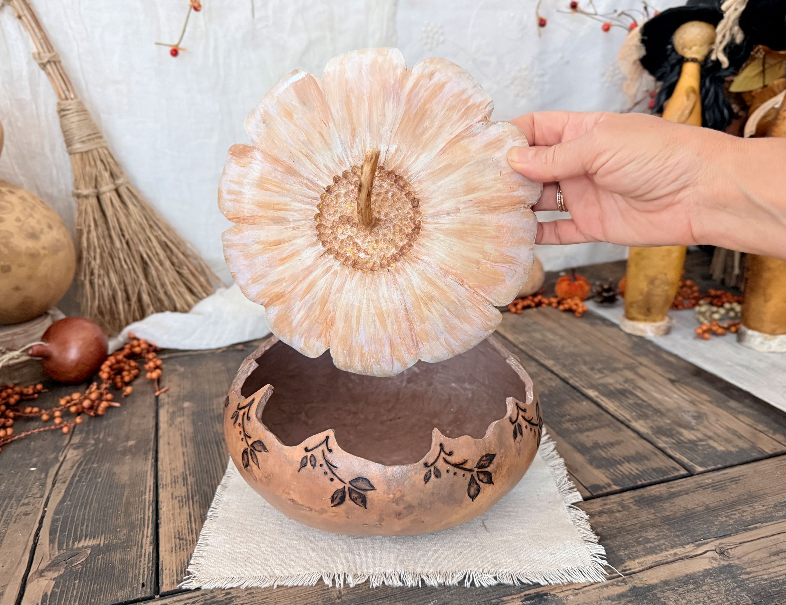 A artisan gourd bowl with my hand holding the lid about the bowl. 