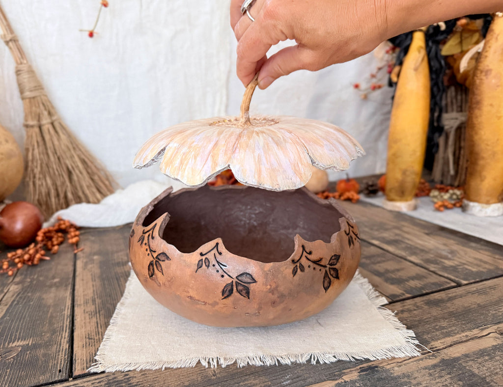 Artisan bowl with a flower blossom lid held in my hand over the bowl.