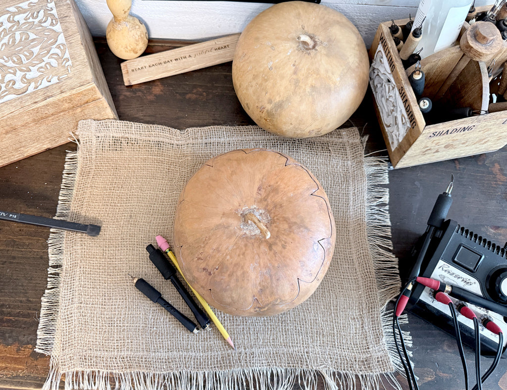 Gourd sitting on desk with wood burning tools near.