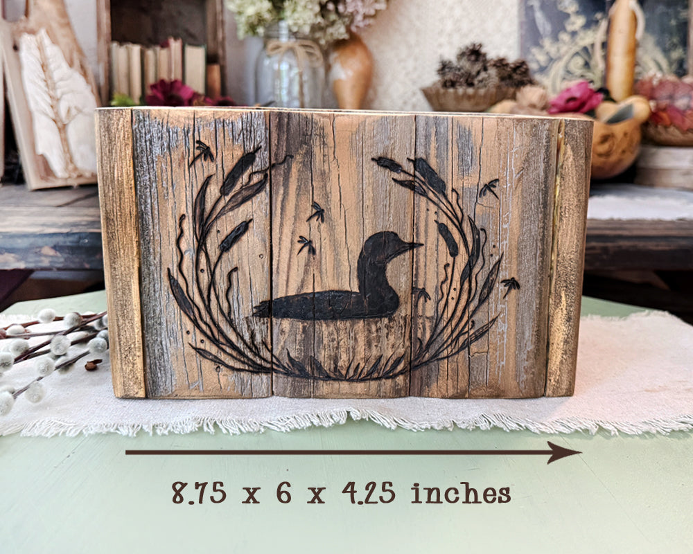 Wooden planter with engraved loon design on a decorative surface