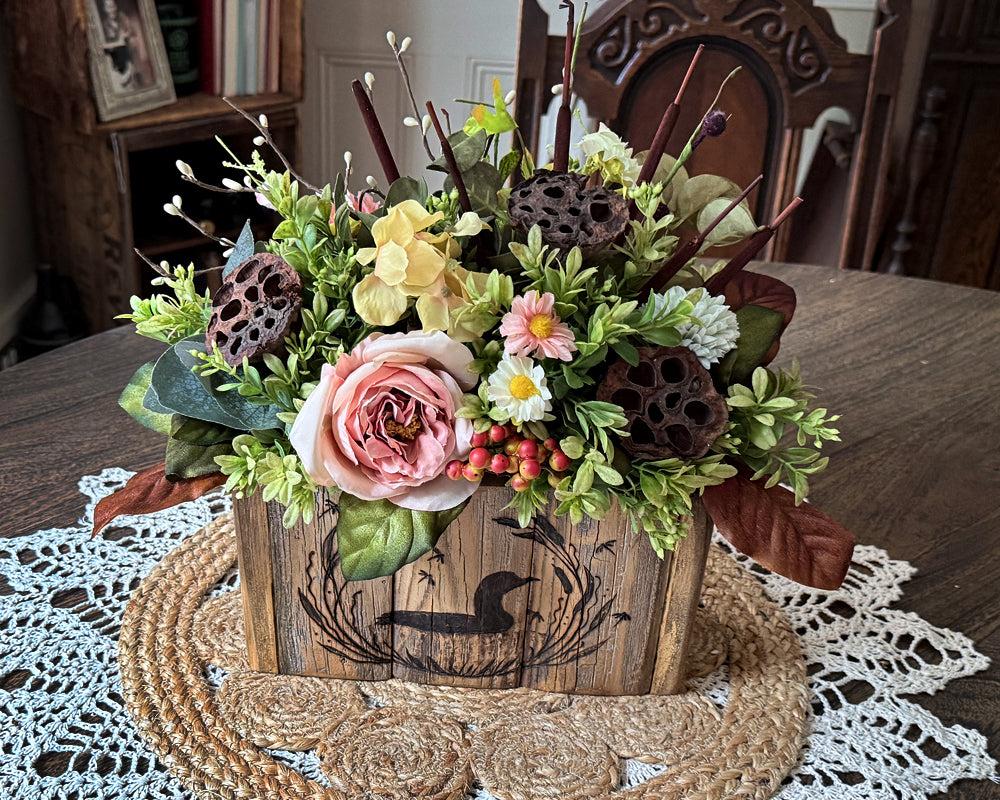 Loon decoration with Floral arrangement in a wooden box on a table with a doily